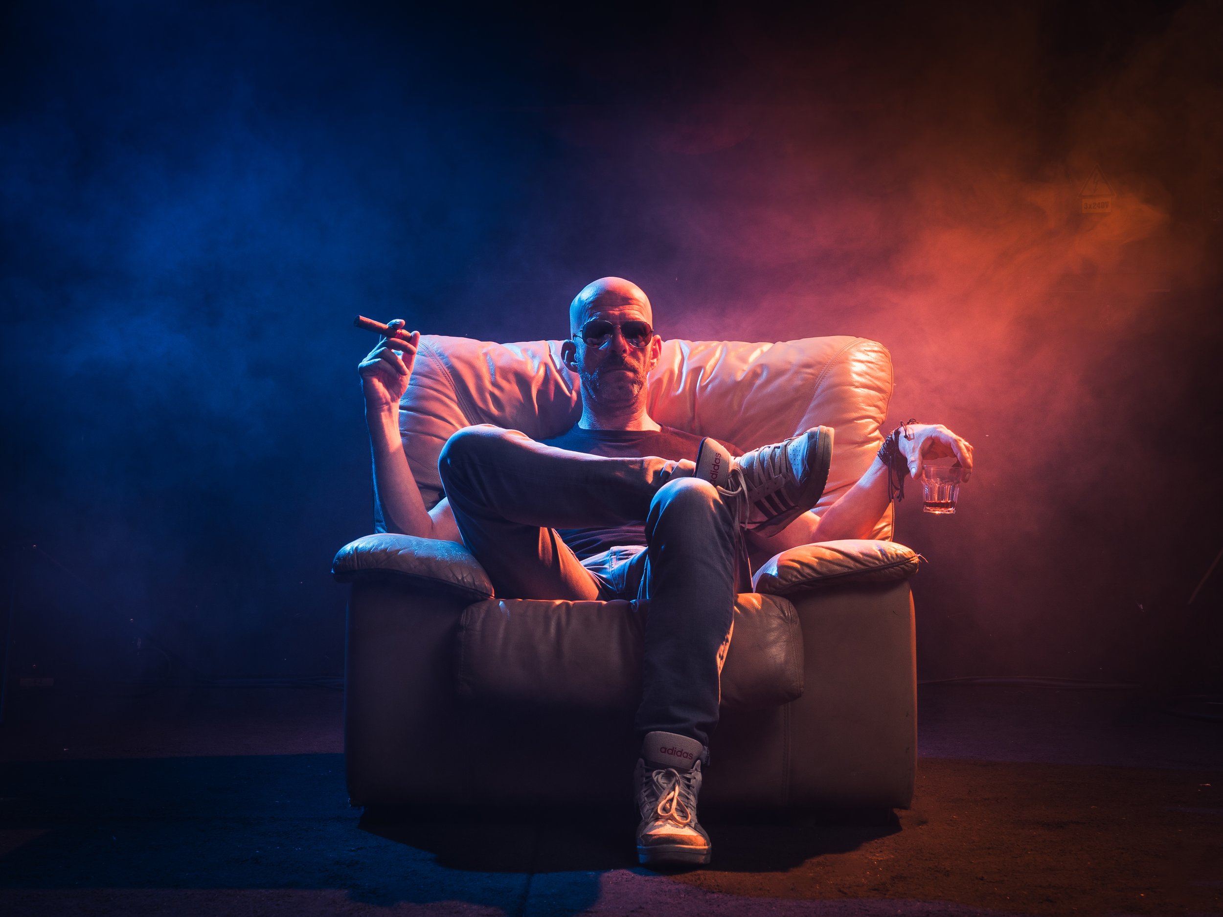 portrait of man sitting in the sofa with a glass alcool and a cigar