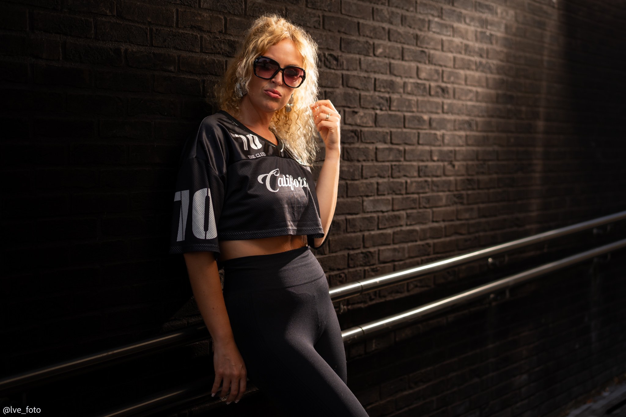 portrait of a blond woman aginst a bric wall