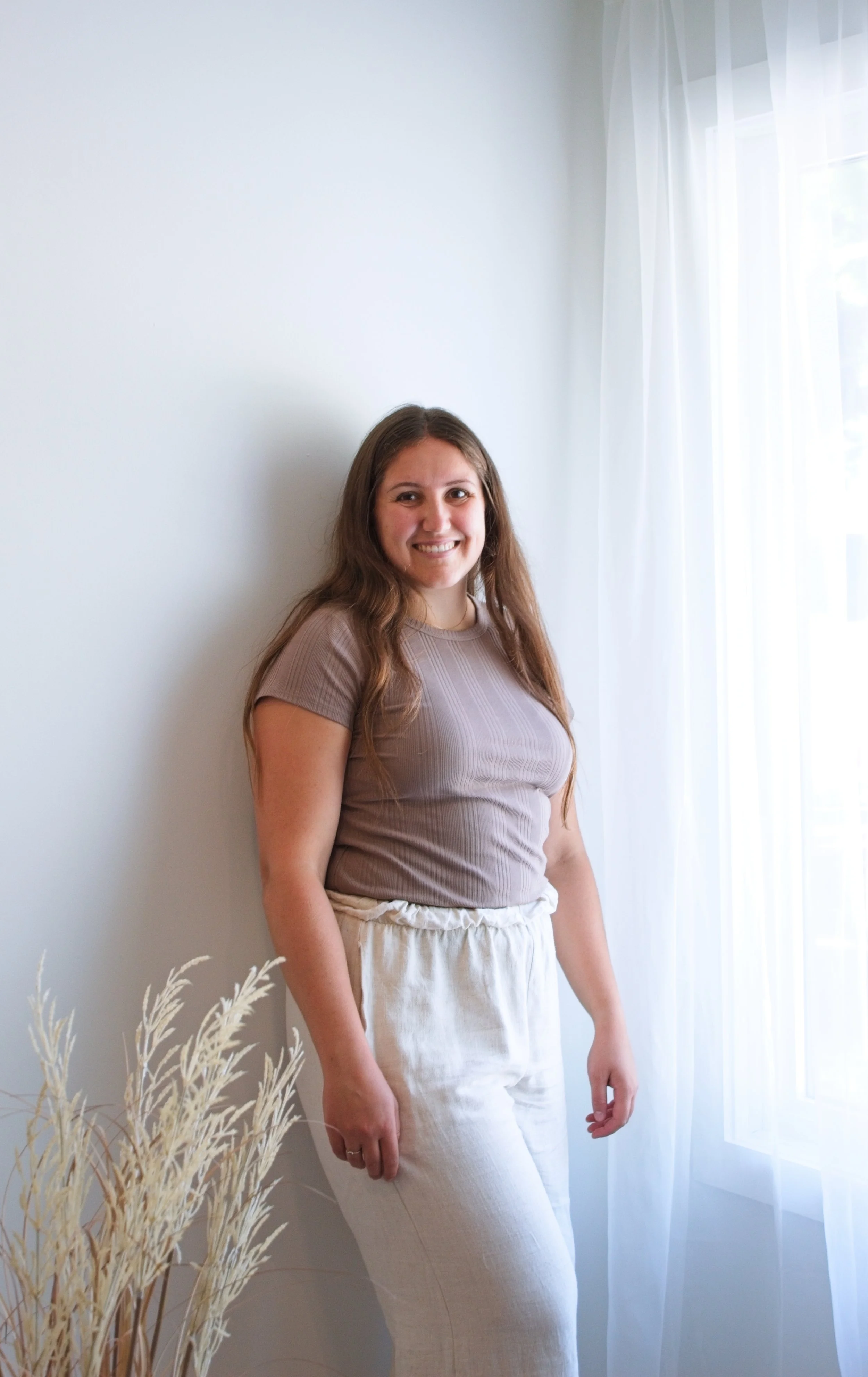 Image of Katie Franklin, Postpartum Doula, Baby-Led Sleep Specialist, and CPST standing by a window at a client home during a postpartum care visit