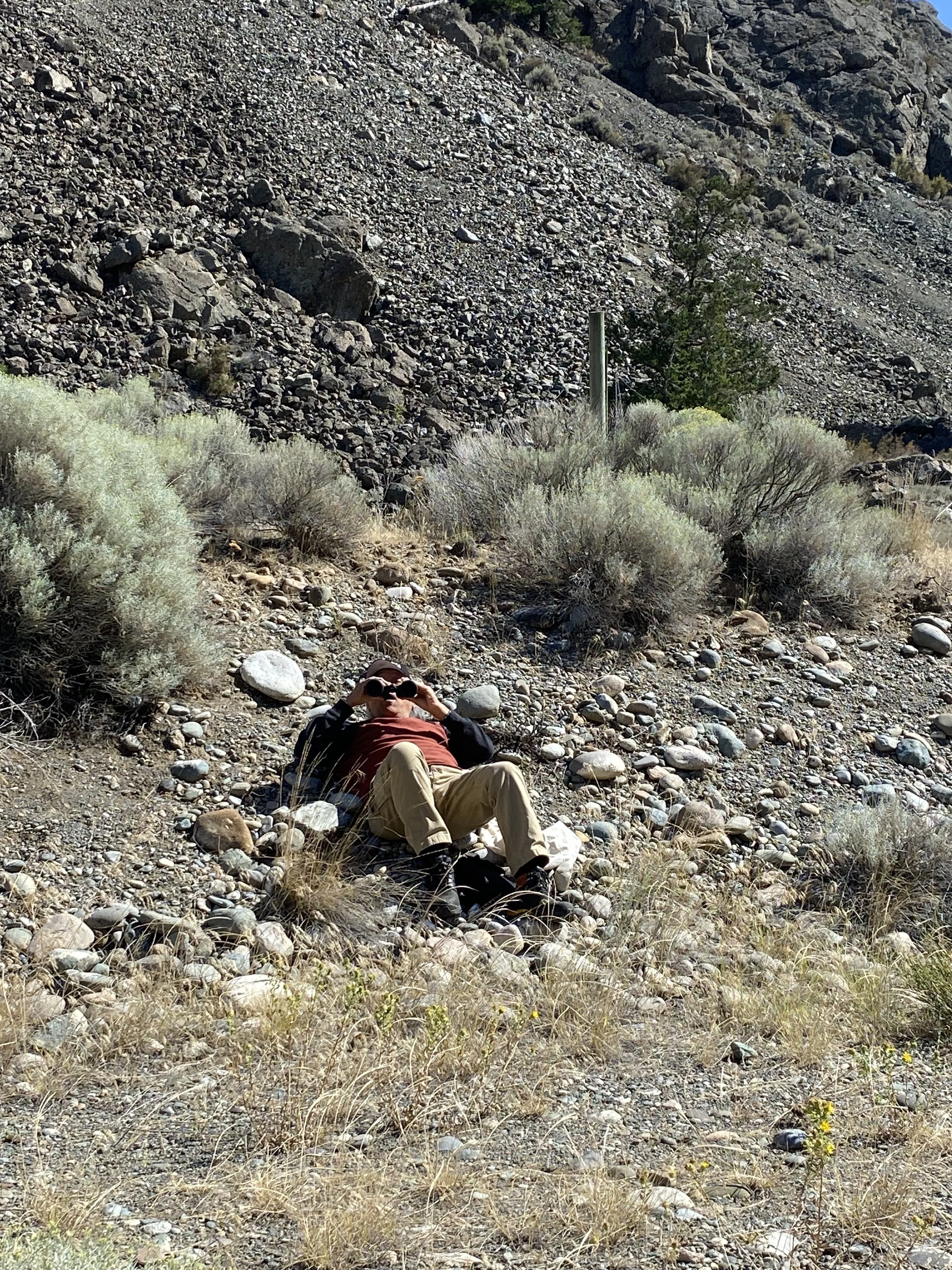 Xwalactun watching fellow artists on the hill through his binoculars