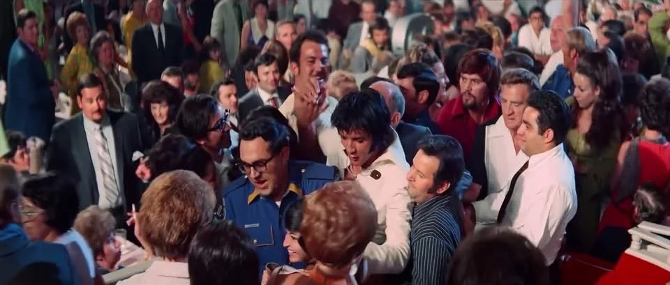 A crowded scene with many people gathered together, some smiling, others talking, at what appears to be an event or gathering.