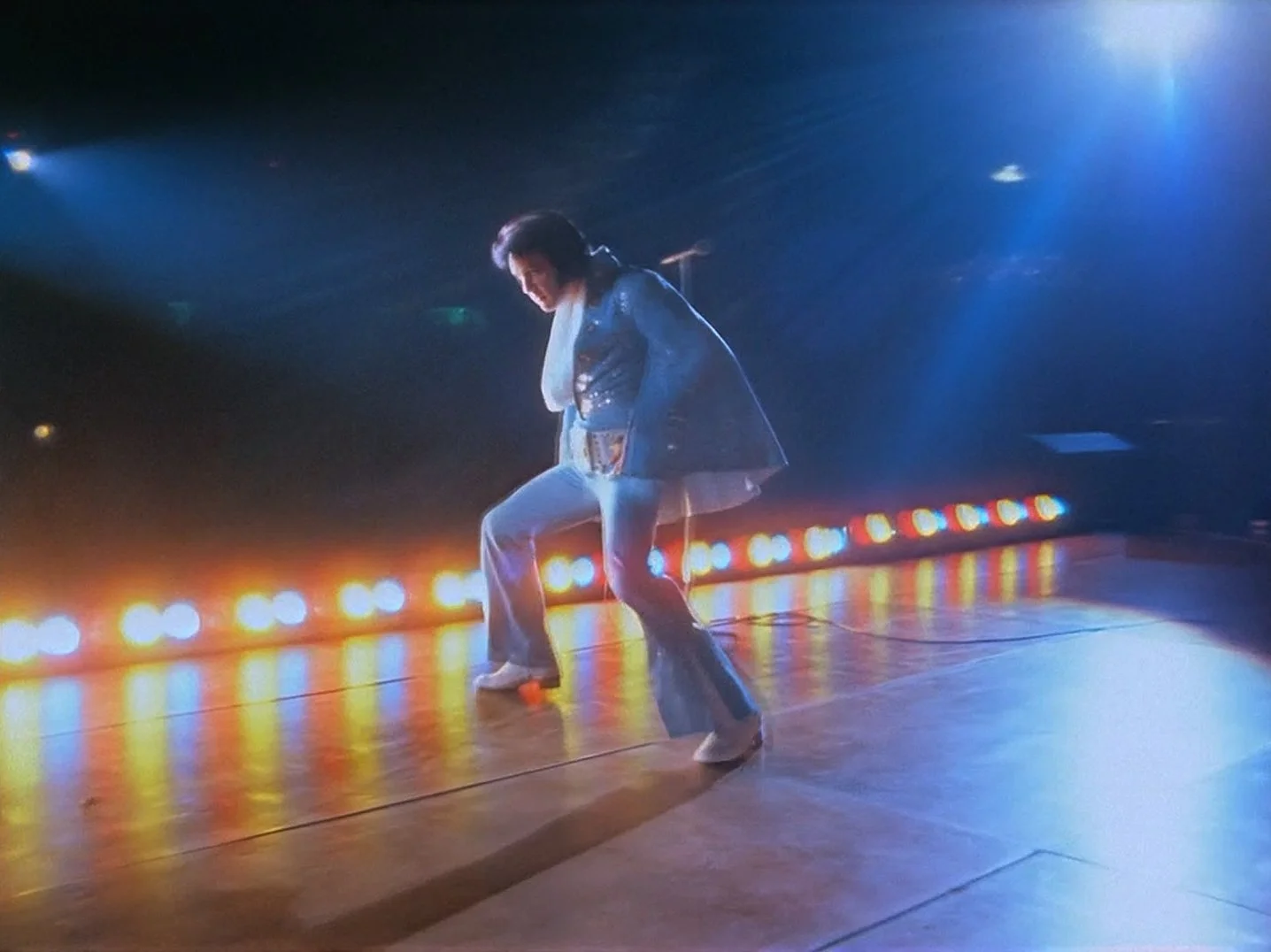 Person rollerskating on a stage with colorful lights in the background.