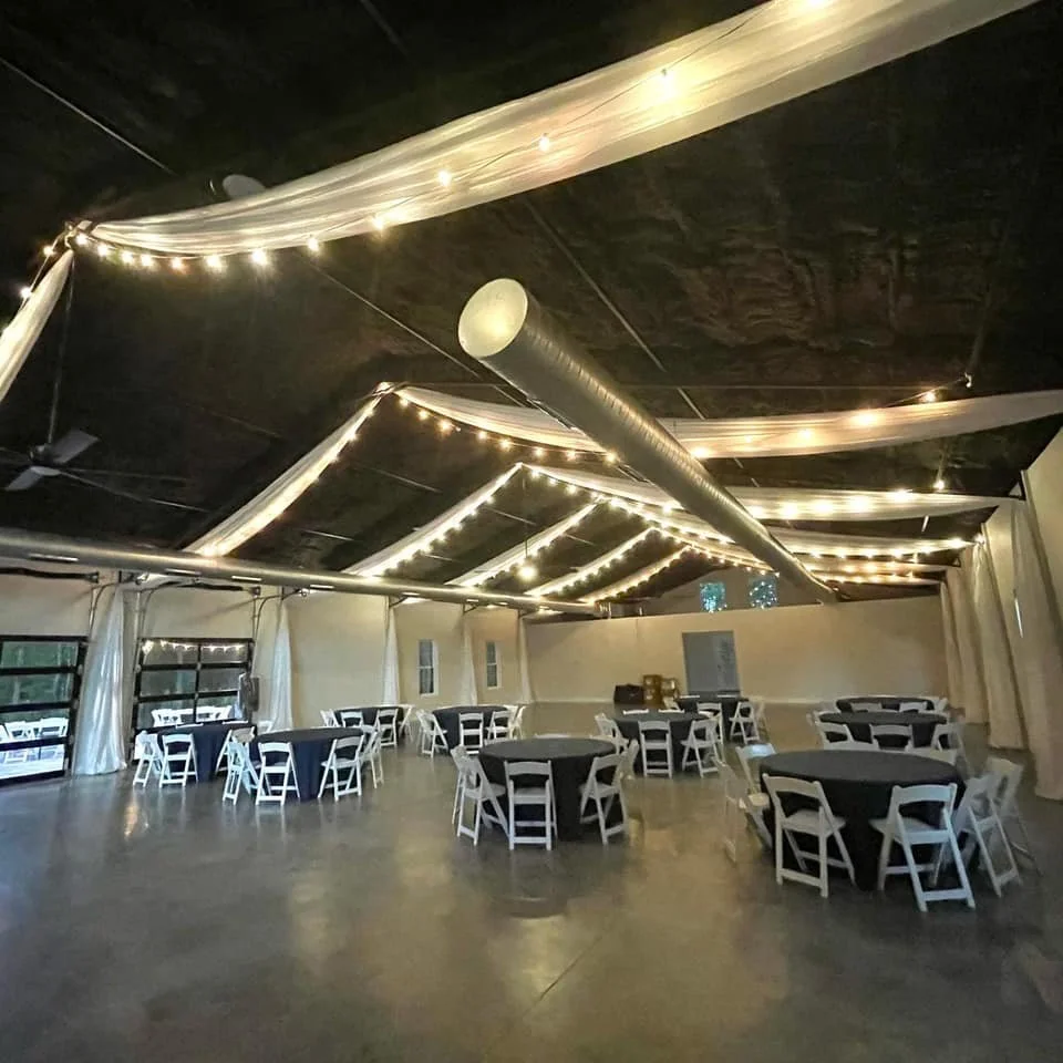 Spacious event hall with string lights and round tables