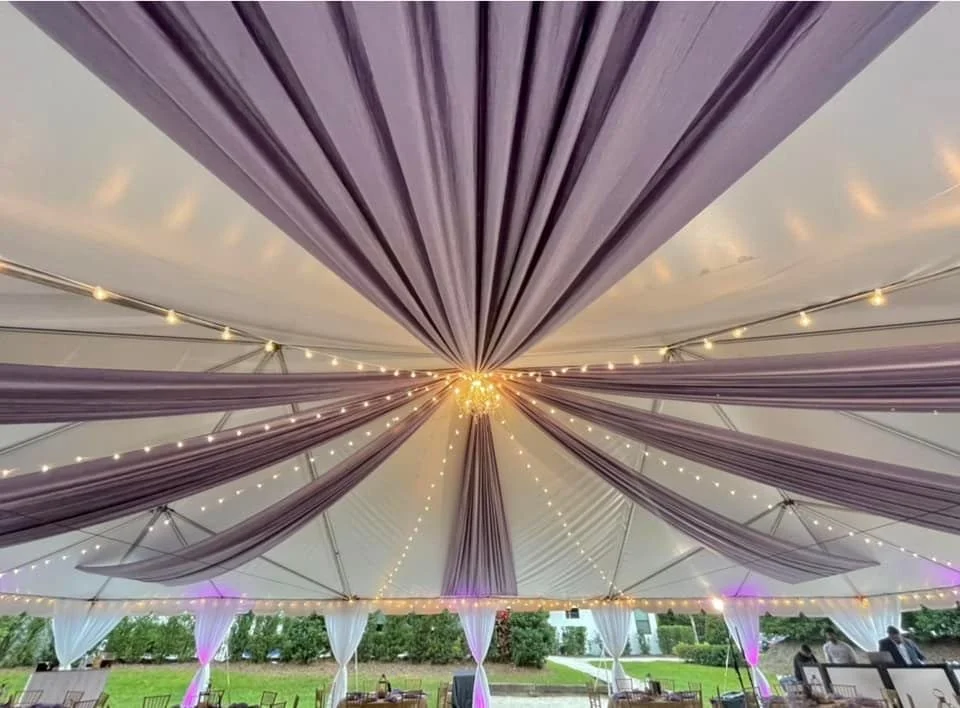 Wedding tent interior with purple drapery and string lights