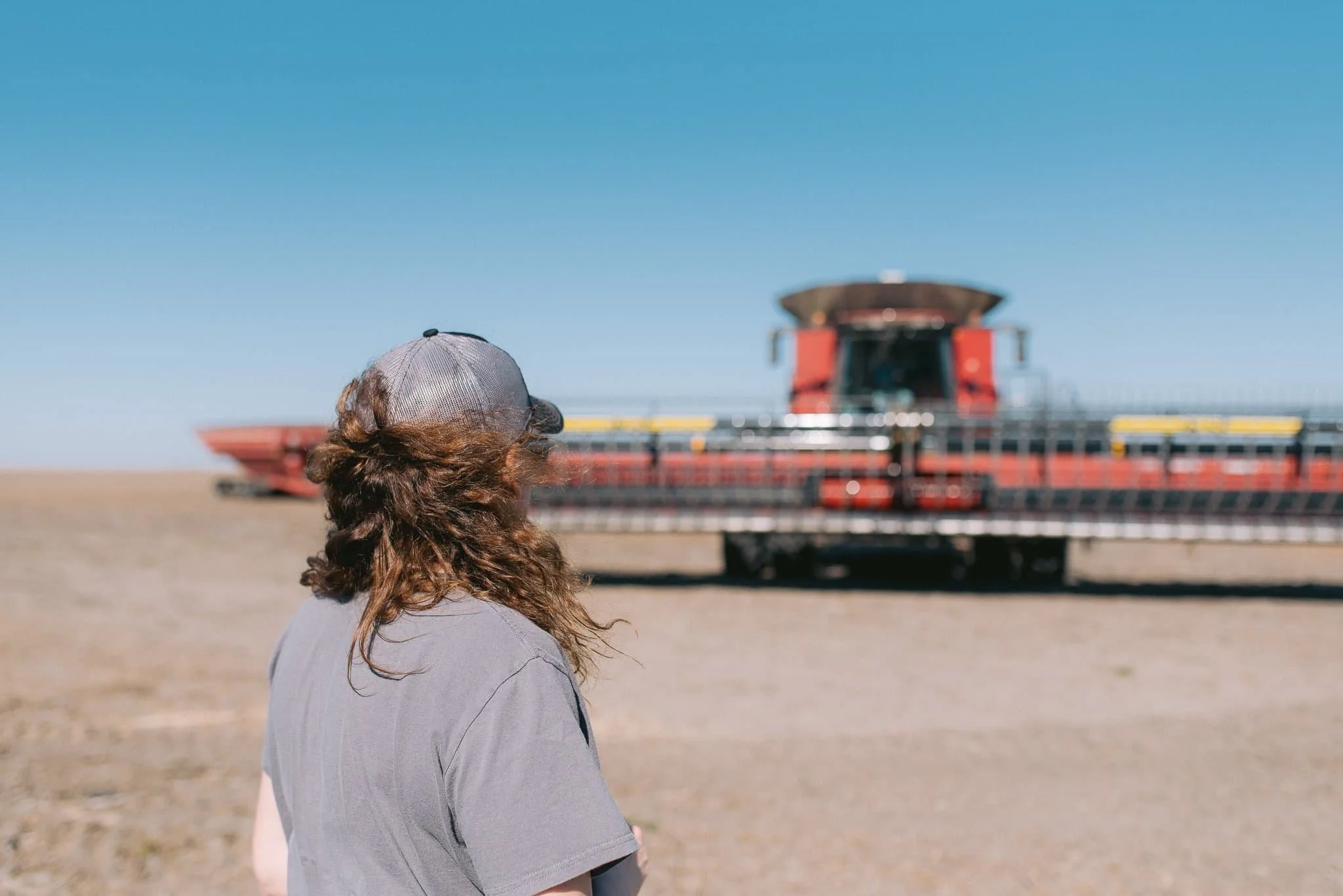 woman in field with combine in background