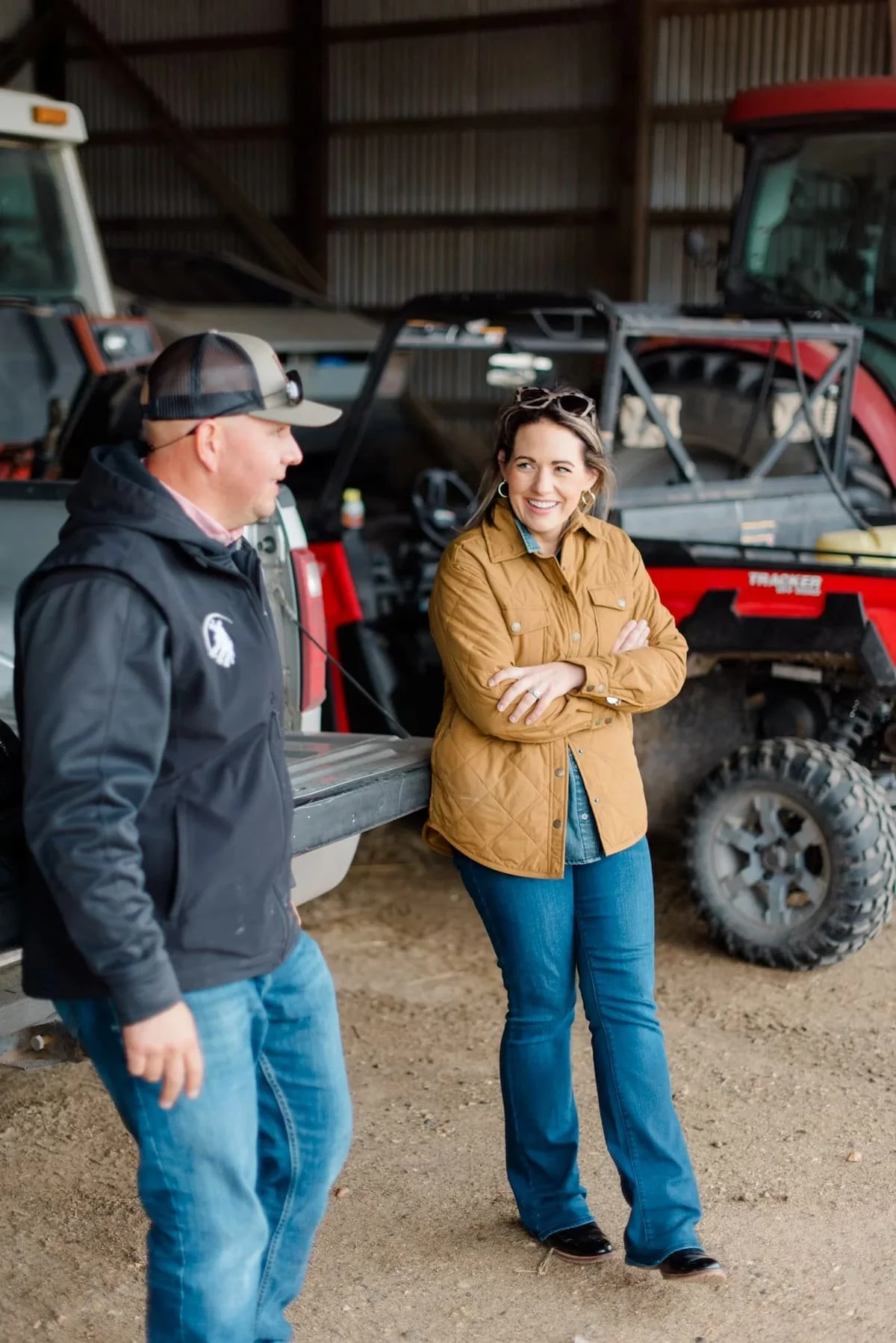 Two farmers talking, leaned up against a motorized vehicle.
