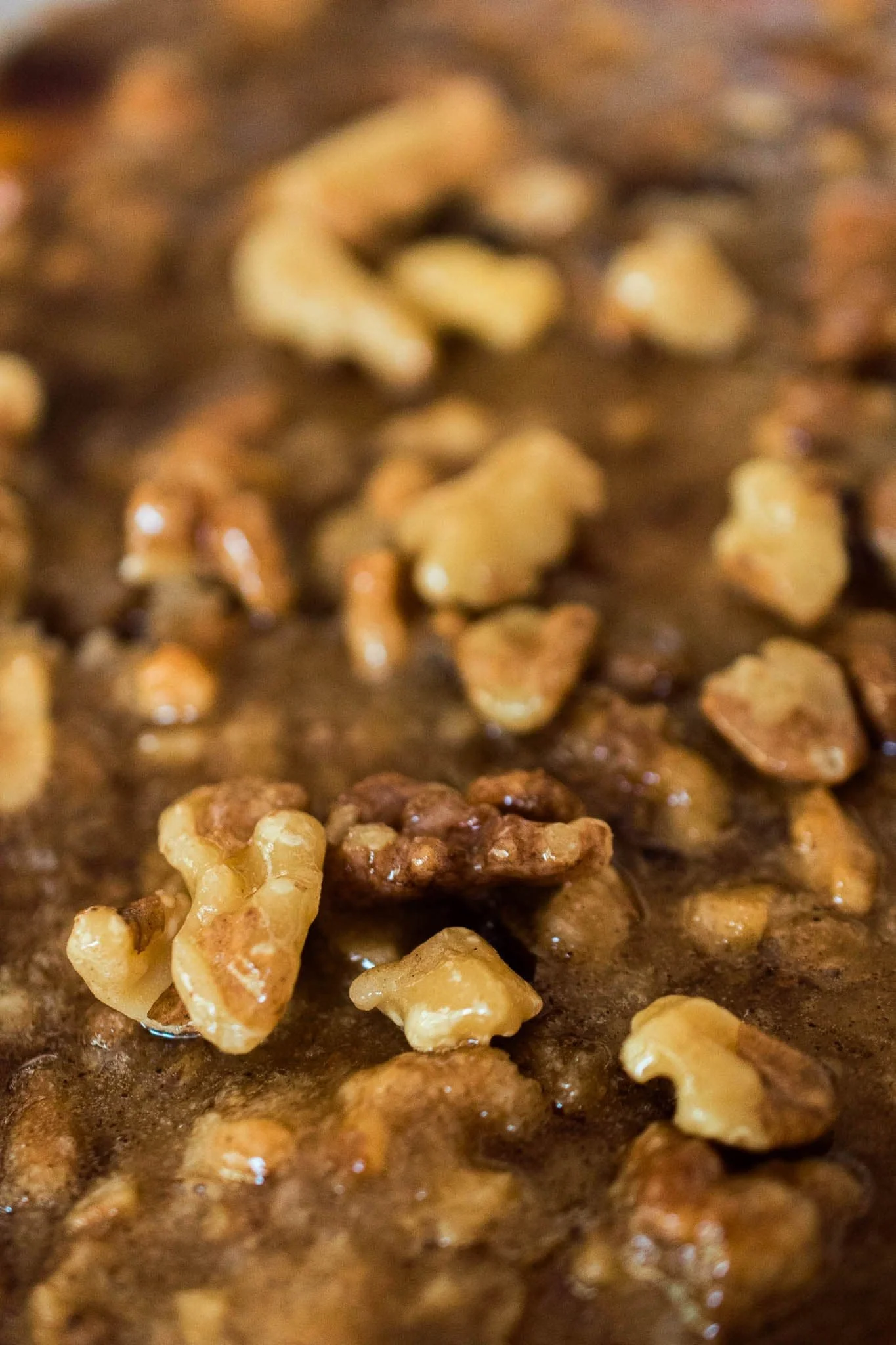 Close up of glazed cashews on a cinnamon streusel swirled sweet potato casserole.