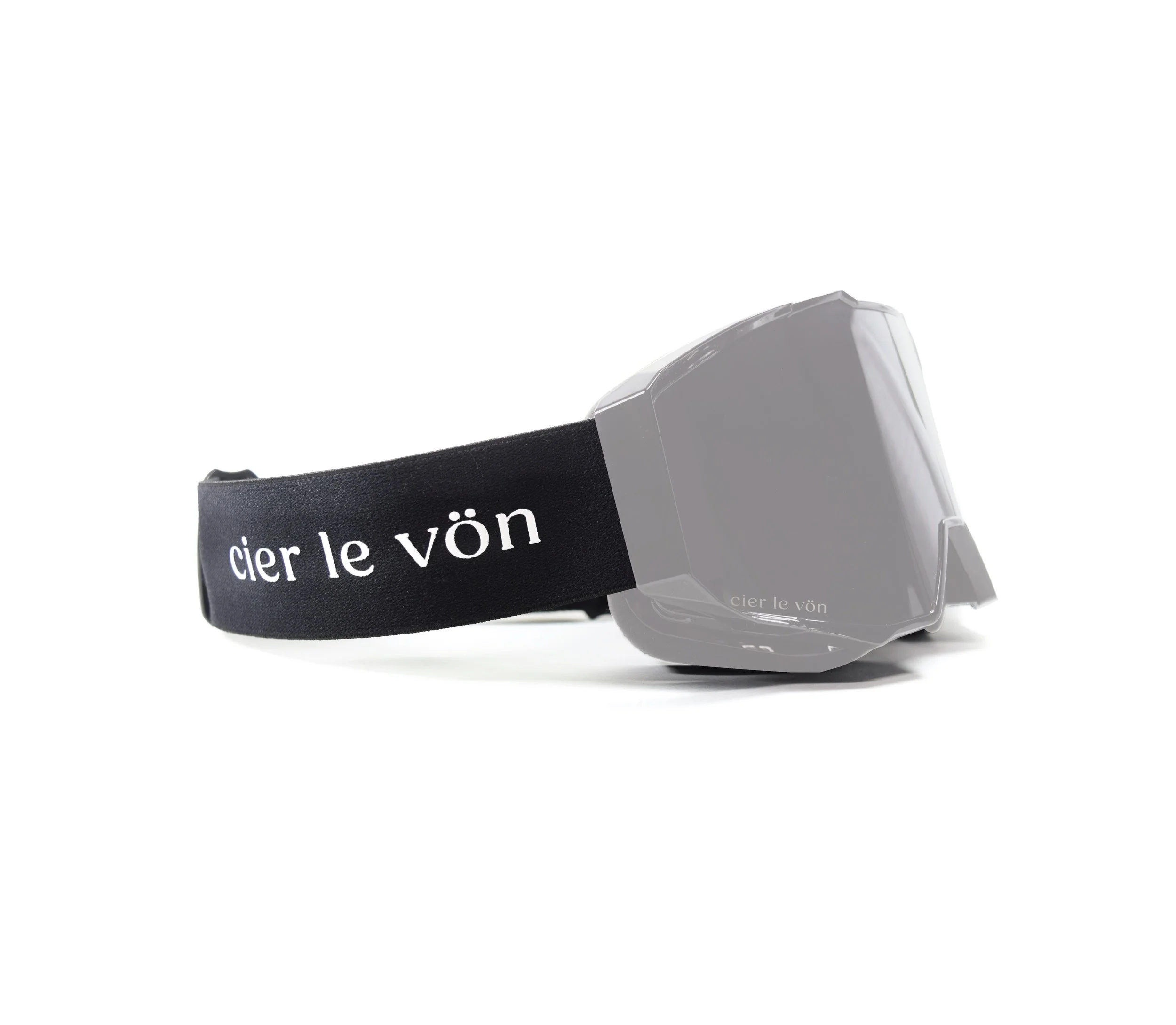 A gray ski or snowboard goggle with a black strap that has white text saying "cier le vön" on it, on a white background.
