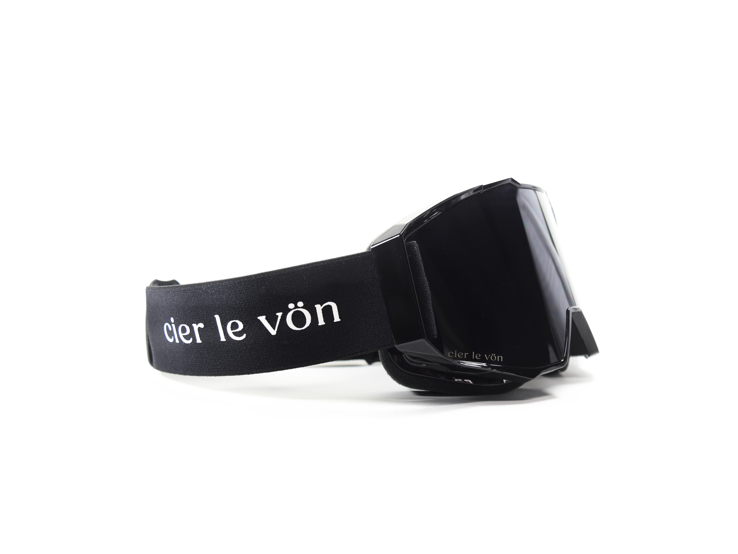 Black ski or snowboarding goggles with a black strap that has white text reading 'cier le vön' printed on it, positioned on a white background.
