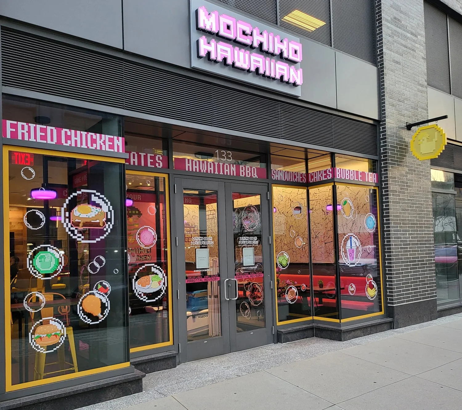 The Mochiko Hawaiian storefront at 133 Guest St, Boston Landing, with a pink pixel sign and yellow window frames