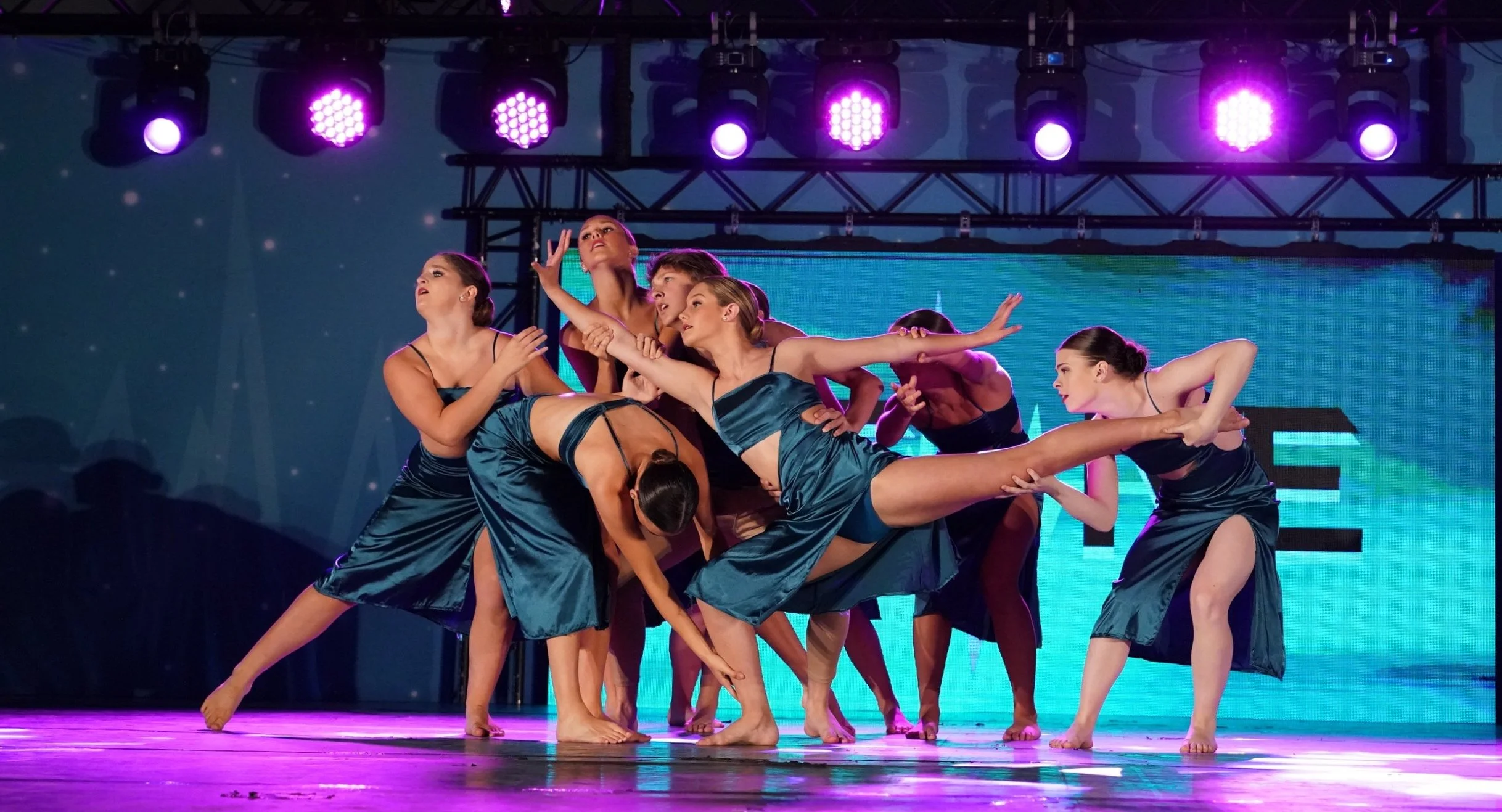 Dance group performance captured live on stage with vibrant lighting and expressive choreography.