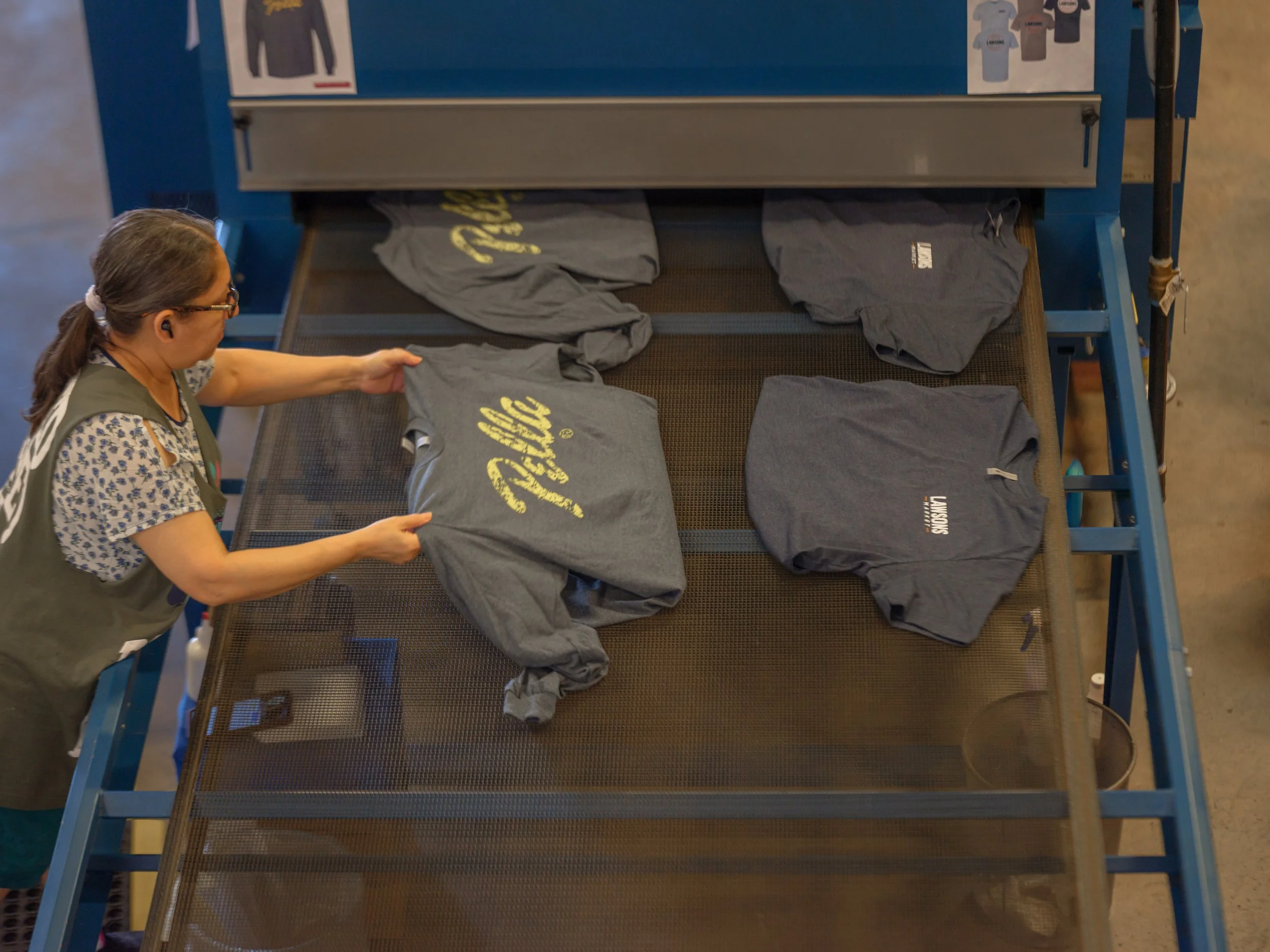 A female worker adding shirts to a moving conveyor belt.