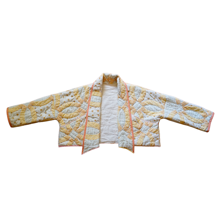 Front view of a yellow and white double wedding ring quilt coat with peach binding