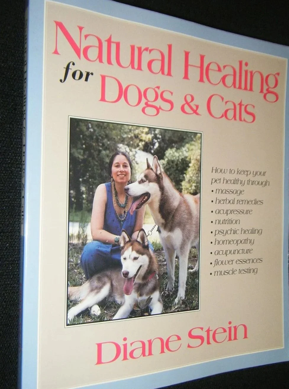 Book cover titled "Natural Healing for Dogs & Cats" by Diane Stein, featuring a woman with two huskies outdoors.