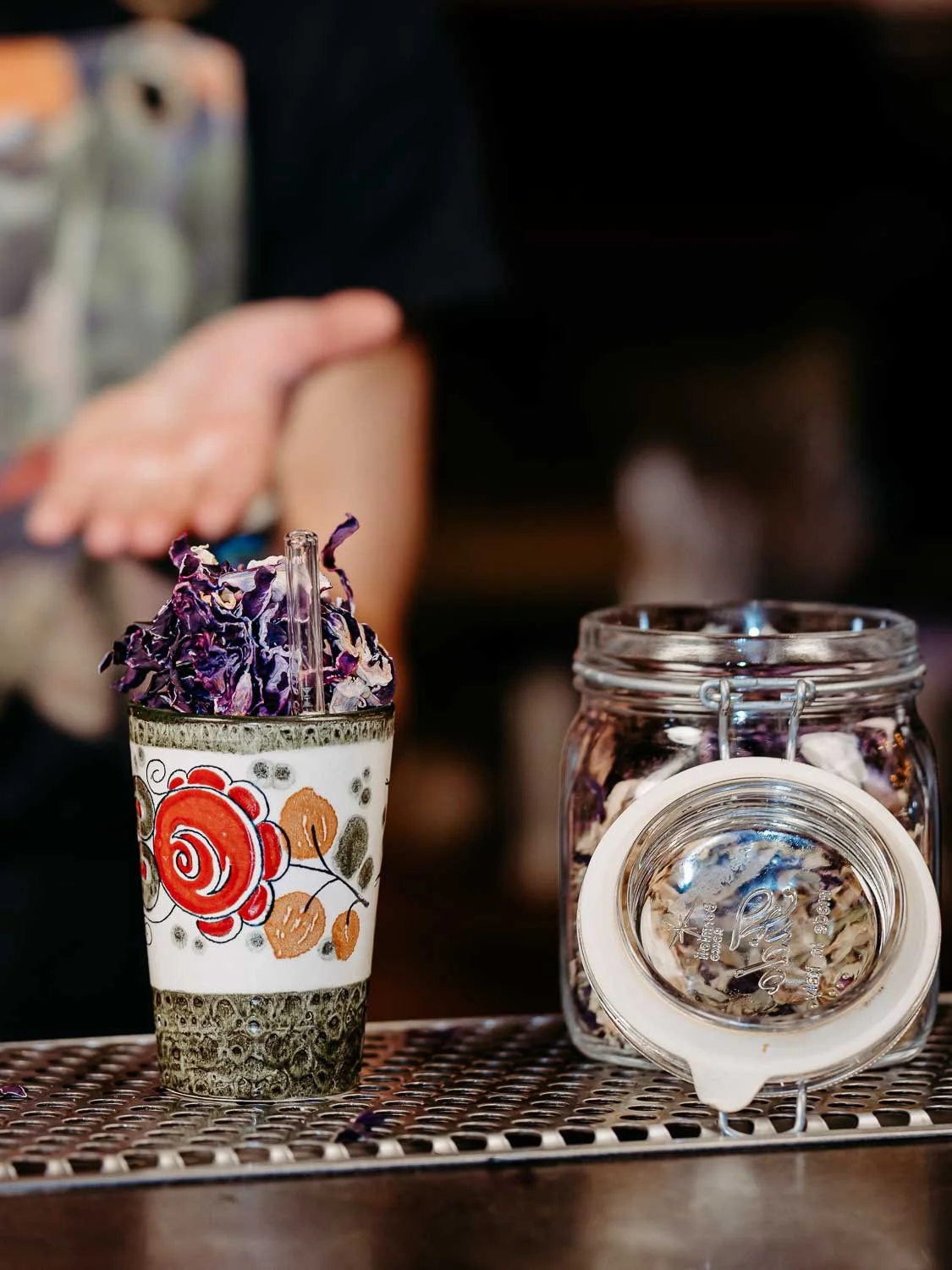 Ein Cocktail bedeckt mit Kraut oin einer Keramiktasse, daneben ein Einmachglas