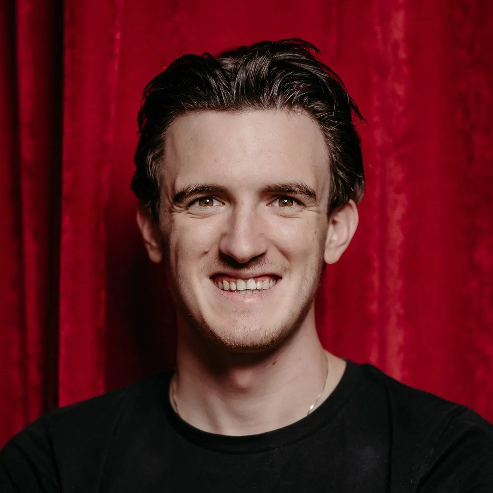 Martin Siprak, ein sympathischer Barkeeper, lächelt in die Kamera vor rotem Vorhang