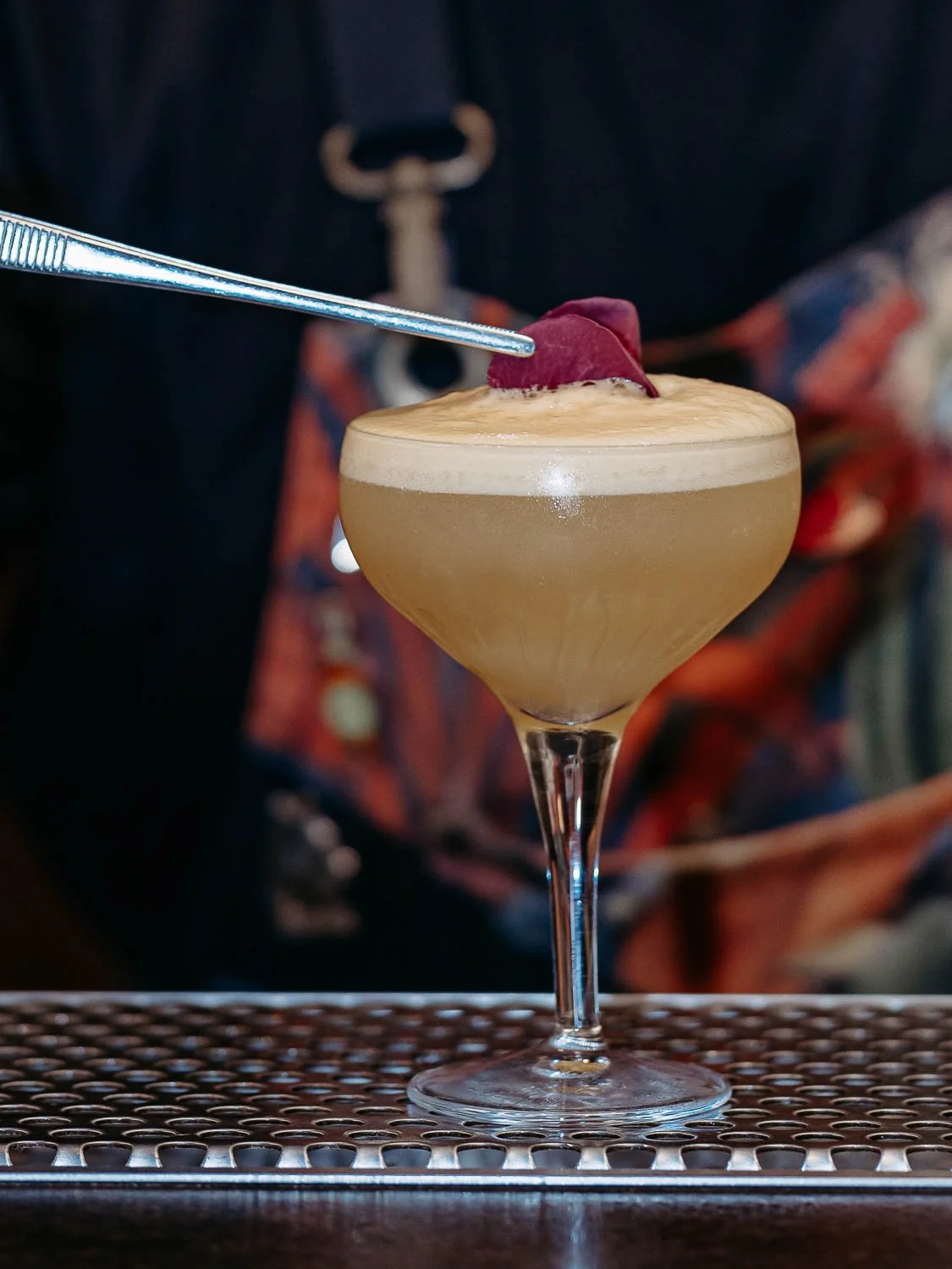 Ein Cocktailglas mit langem Stihl wird garniert mit einer Rosenblüte