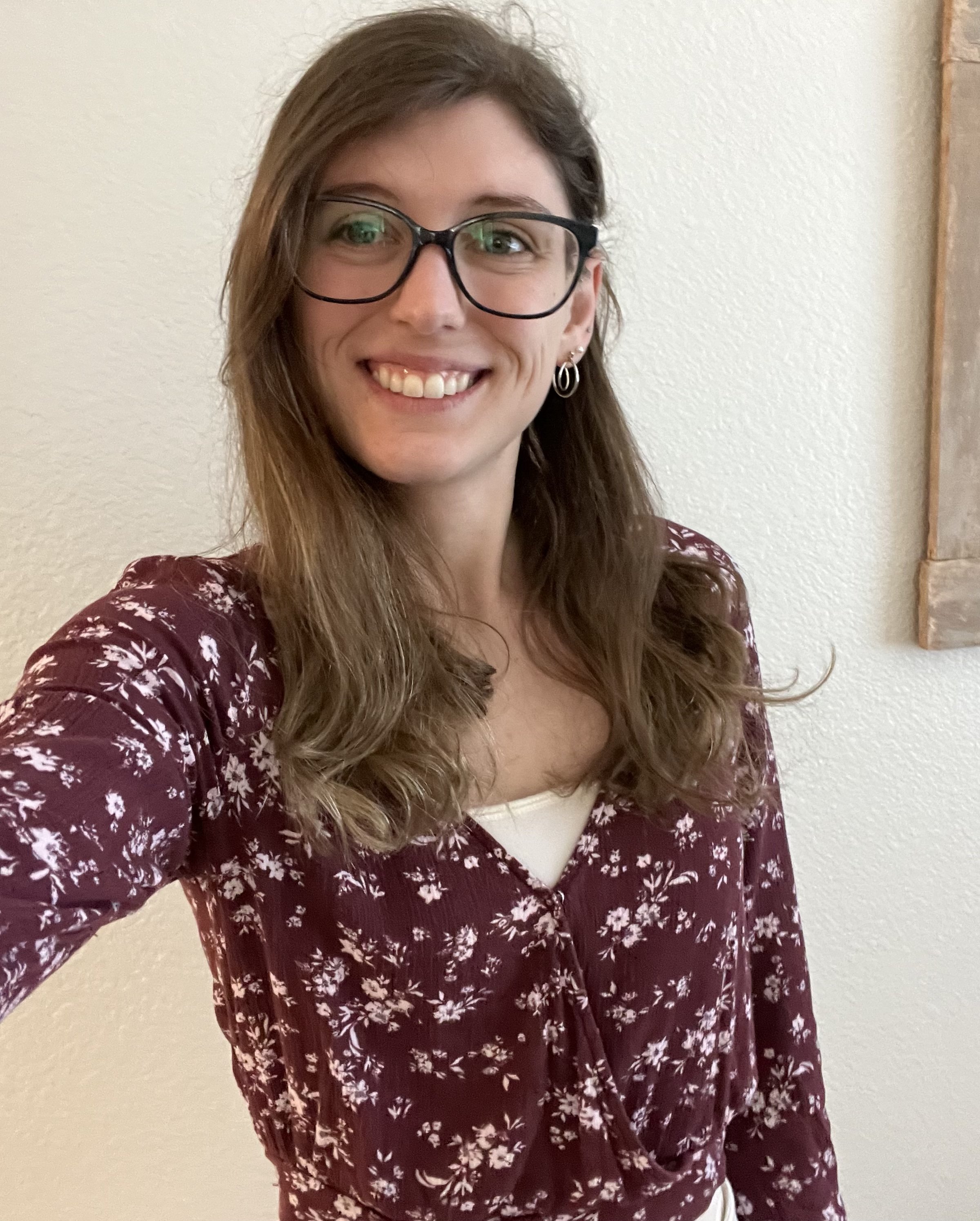 A selfie of me, a women's health and wellness copywriter, in a purple floral shirt.