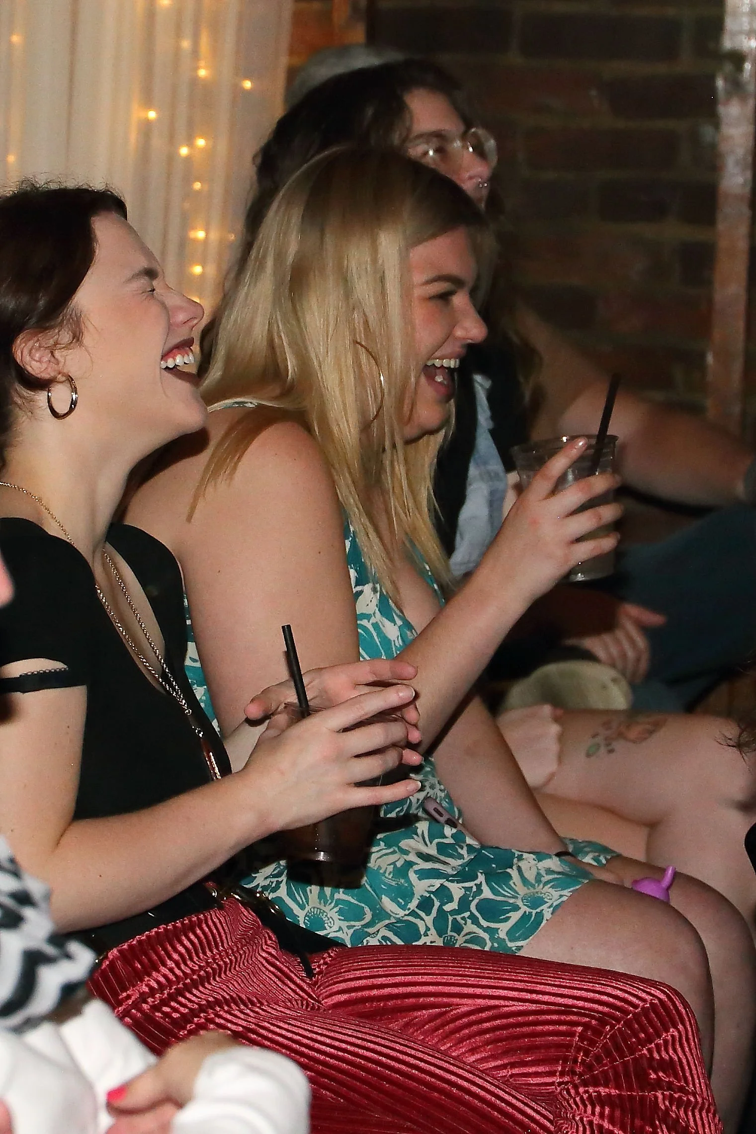 Group of people sitting together enjoying drinks and laughing at a social gathering.
