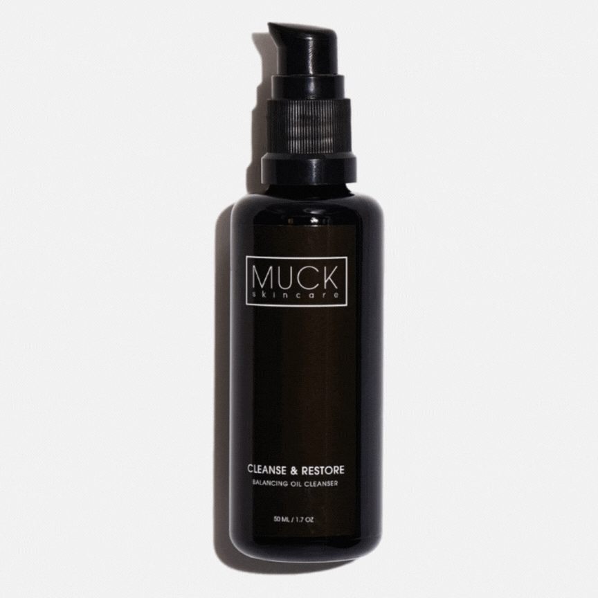 A brown bottle of Muck skincare Cleanse & Restore balancing oil cleanser with a black pump dispenser against a white background,  closed and then opened.