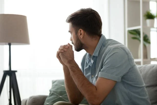 Person sitting quietly with hands folded, reflecting during a moment of anxiety and emotional overwhelm