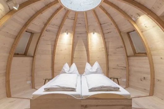 Ein Schlafzimmer mit einem runden, holzverkleideten Raum und einem Bett in der Mitte.