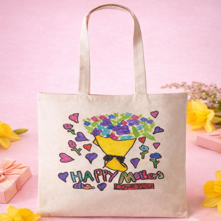 A canvas tote bag with a colorful drawing of a bouquet of flowers, surrounded by hearts, with the text "Happy Mother's Love You" written in colorful letters.