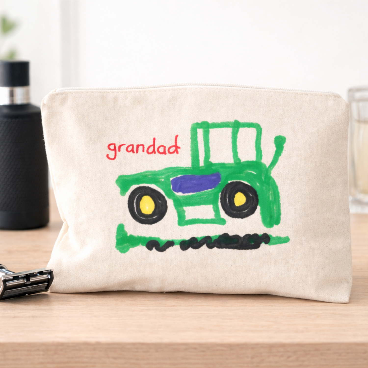 A cotton wash bag with a child's drawing printed on the front and the words Grandad printed in red