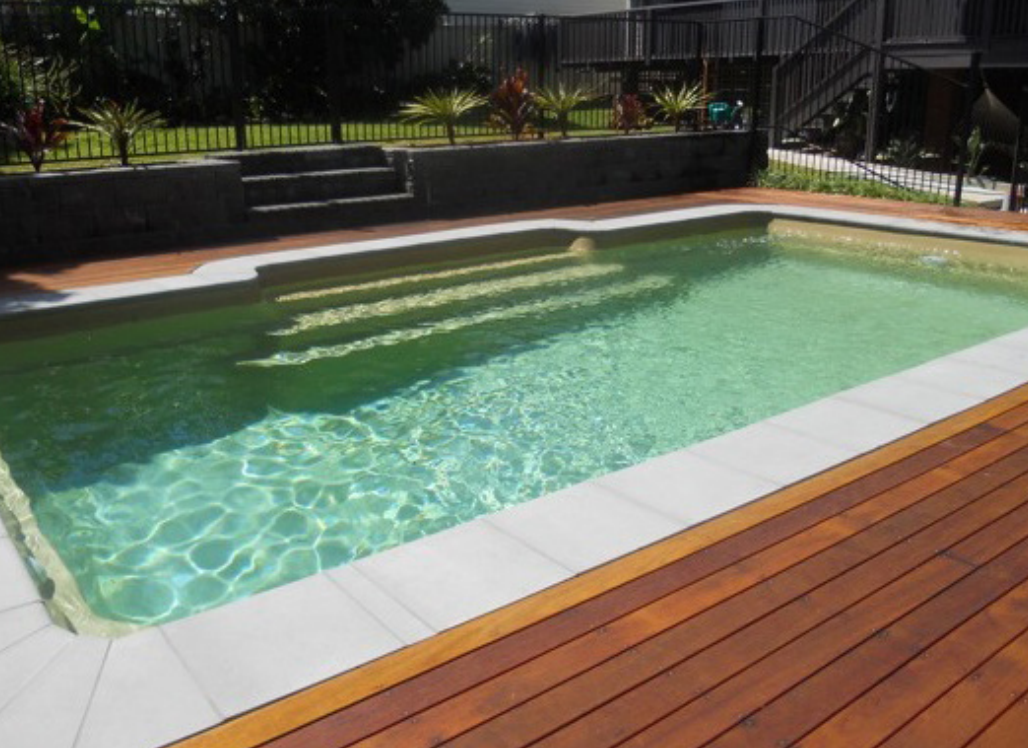 Empty rectangular swimming pool with light blue tiles around it.