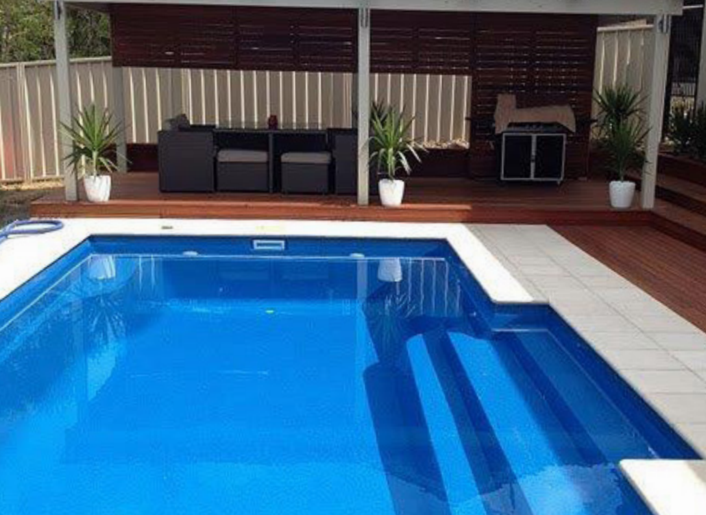Empty swimming pool with blue water and white tiled deck.
