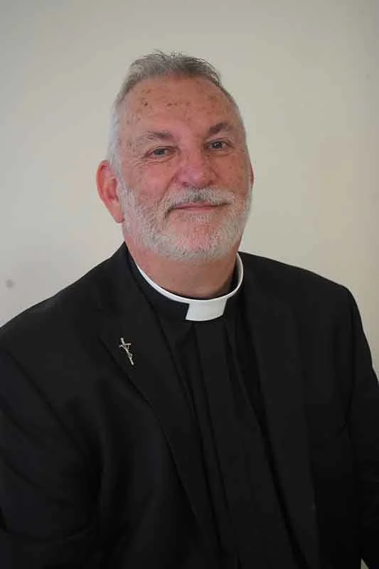 Smiling clergyman in black suit with white clerical collar