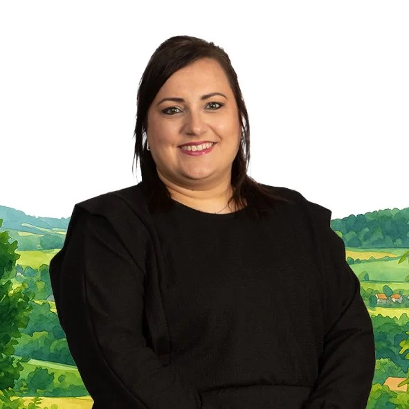 Portret van een lachende vrouw met donkerbruin haar en een zwarte jurk, voor een geanimeerde achtergrond van landelijke landschapen.