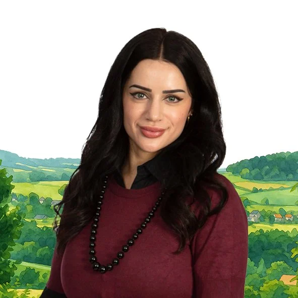 Een vrouw met zwarte haar en een rode trui, poseert voor een illustratie van een landschap met groene heuvels en huizen.