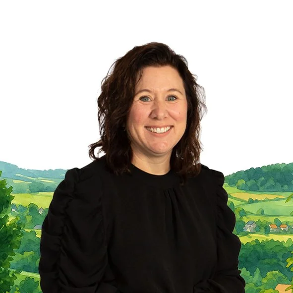 Een lachende vrouw met bruin, golvend haar voor een achtergrond van een pittige illustratie van een landschap met groene heuvels en dorpjes.