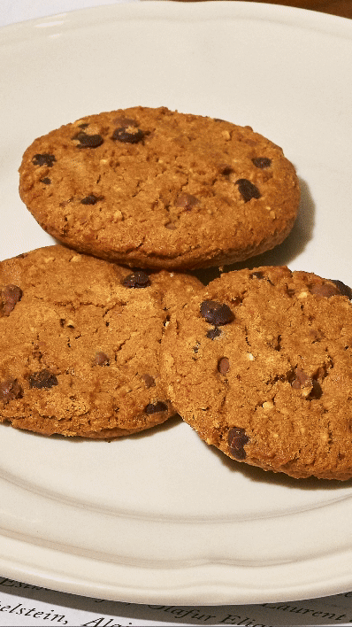 Trois cookies aux pépites de chocolat sur une assiette blanche.