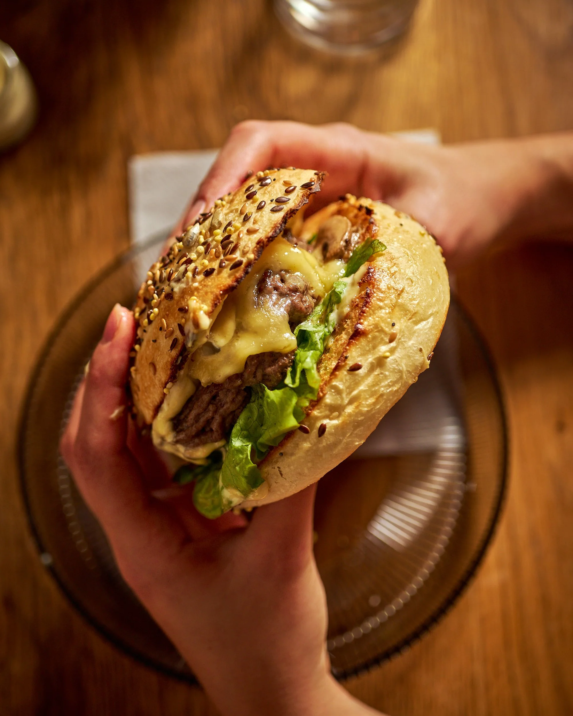 Un sandwich avec un pain au sésame, du fromage fondu, de la viande hachée, de la laitue, et des graines de sésame.