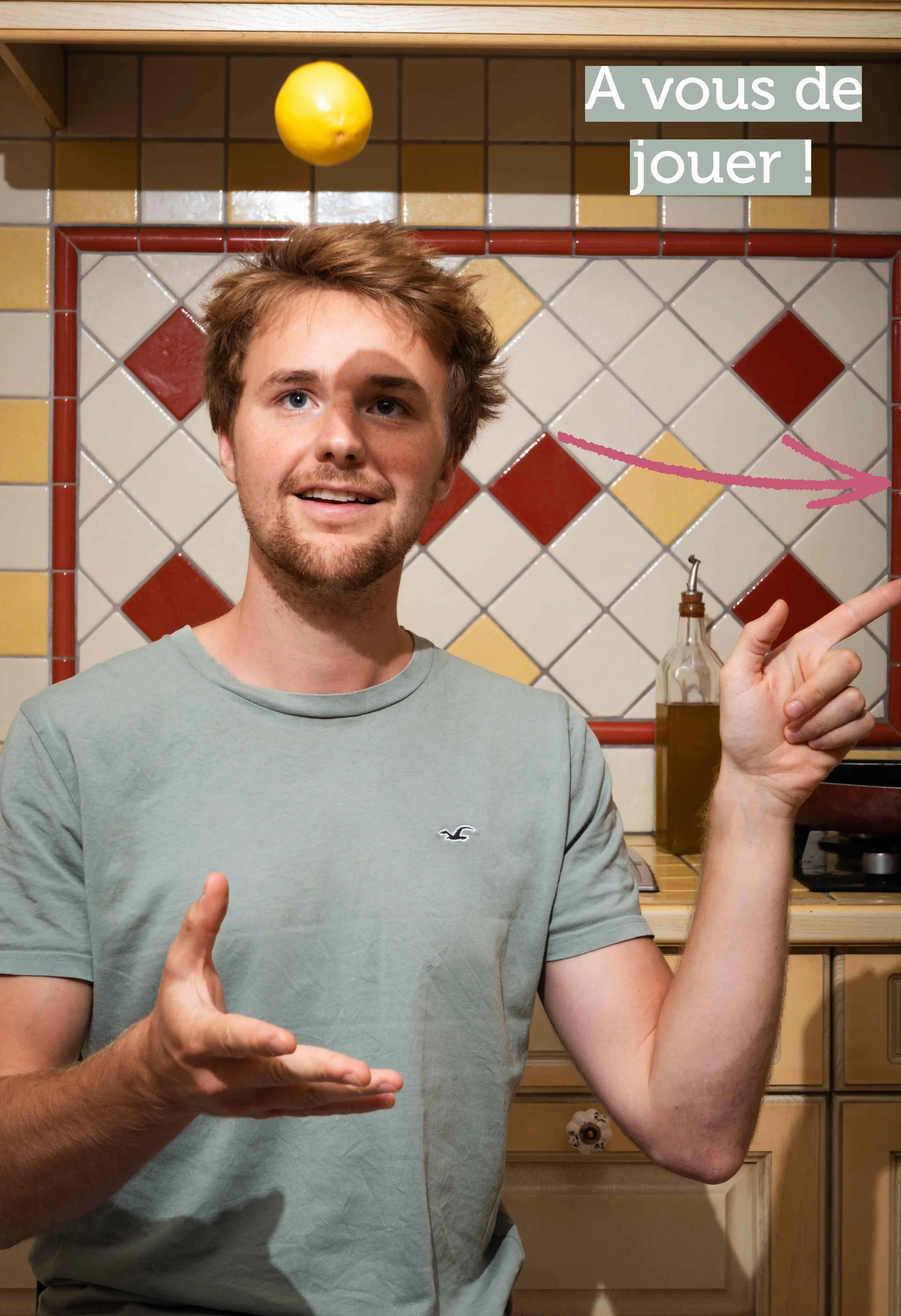 Un homme souriant joue avec un citron jaune en apesanteur dans une cuisine avec un carreau rouge et blanc. Texte : « À vous de jouer ! »