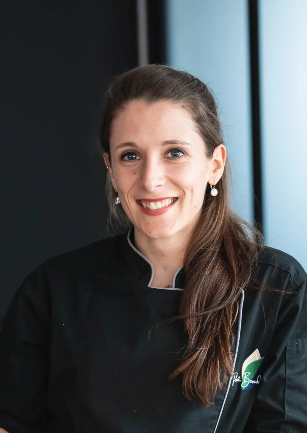 Femme souriante portant une tenue de chef.