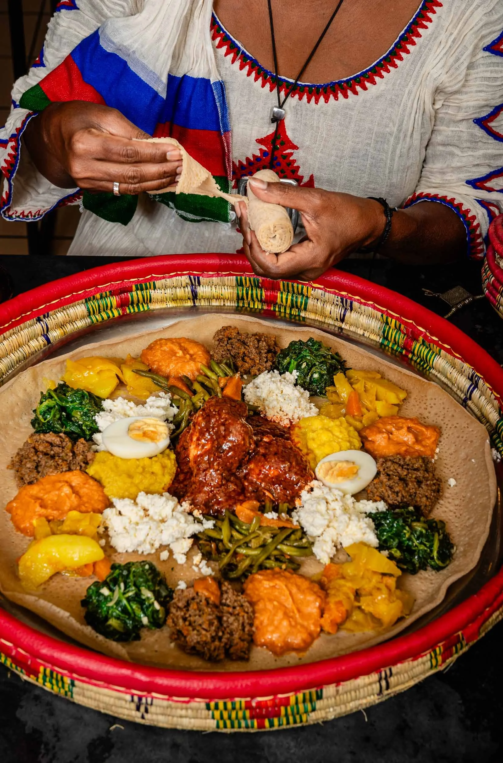 Une cliente éthiopienne déchire l'injara et s'apprête à consommer la nourriture éthiopienne du restaurant Messob à Lyon