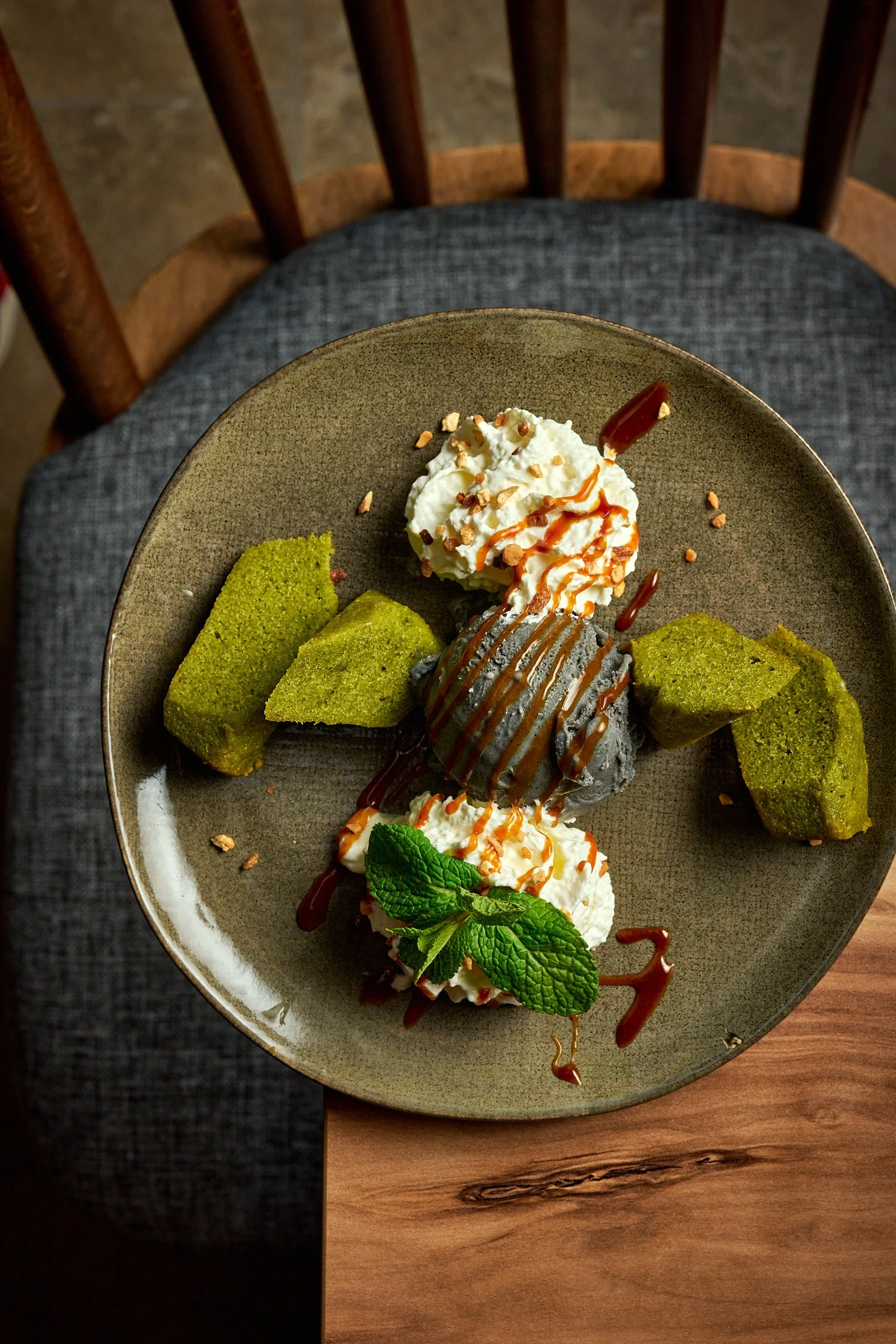 Dessert avec deux boules de glace, gâteau vert, chantilly, menthe et caramel.