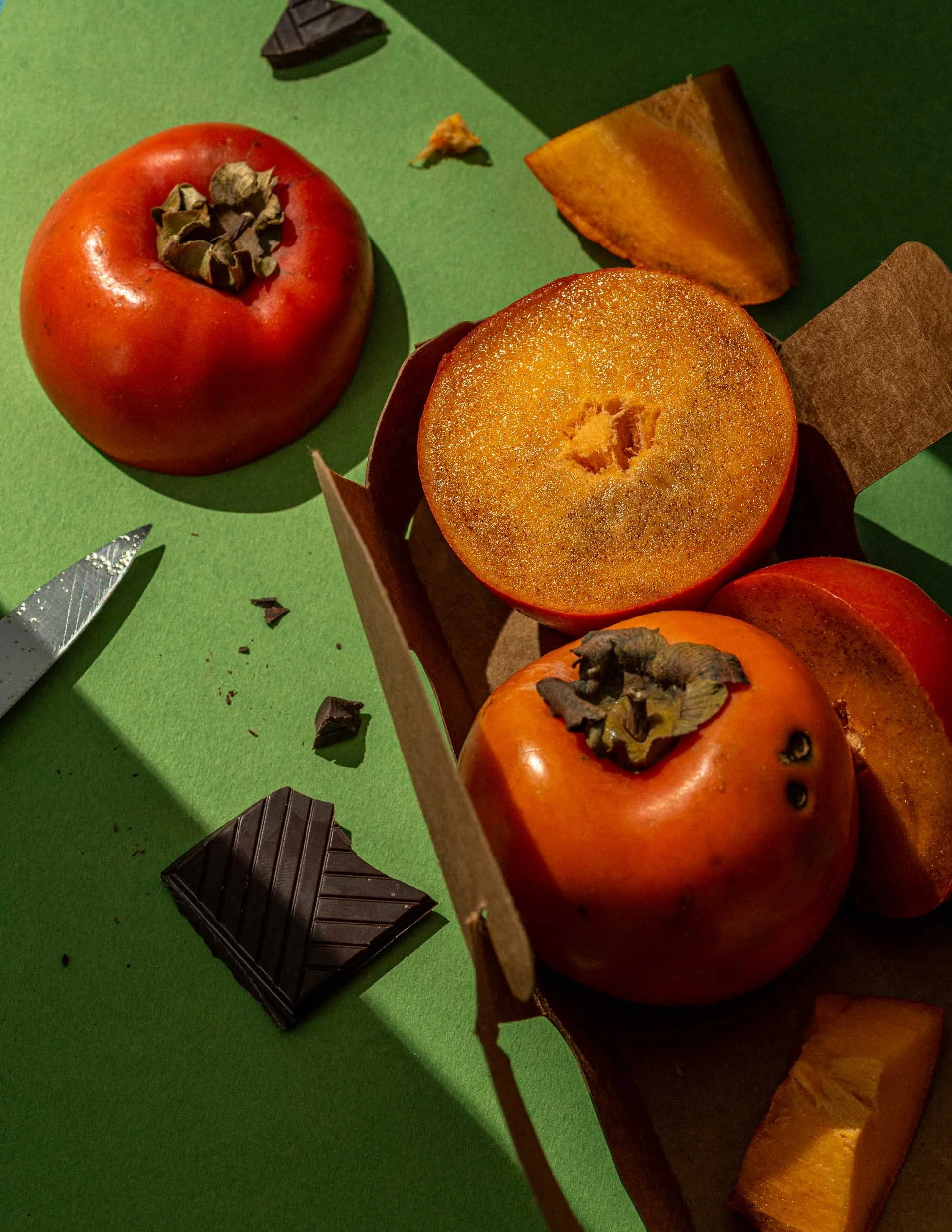 Kakis et morceaux de chocolat sur fond vert