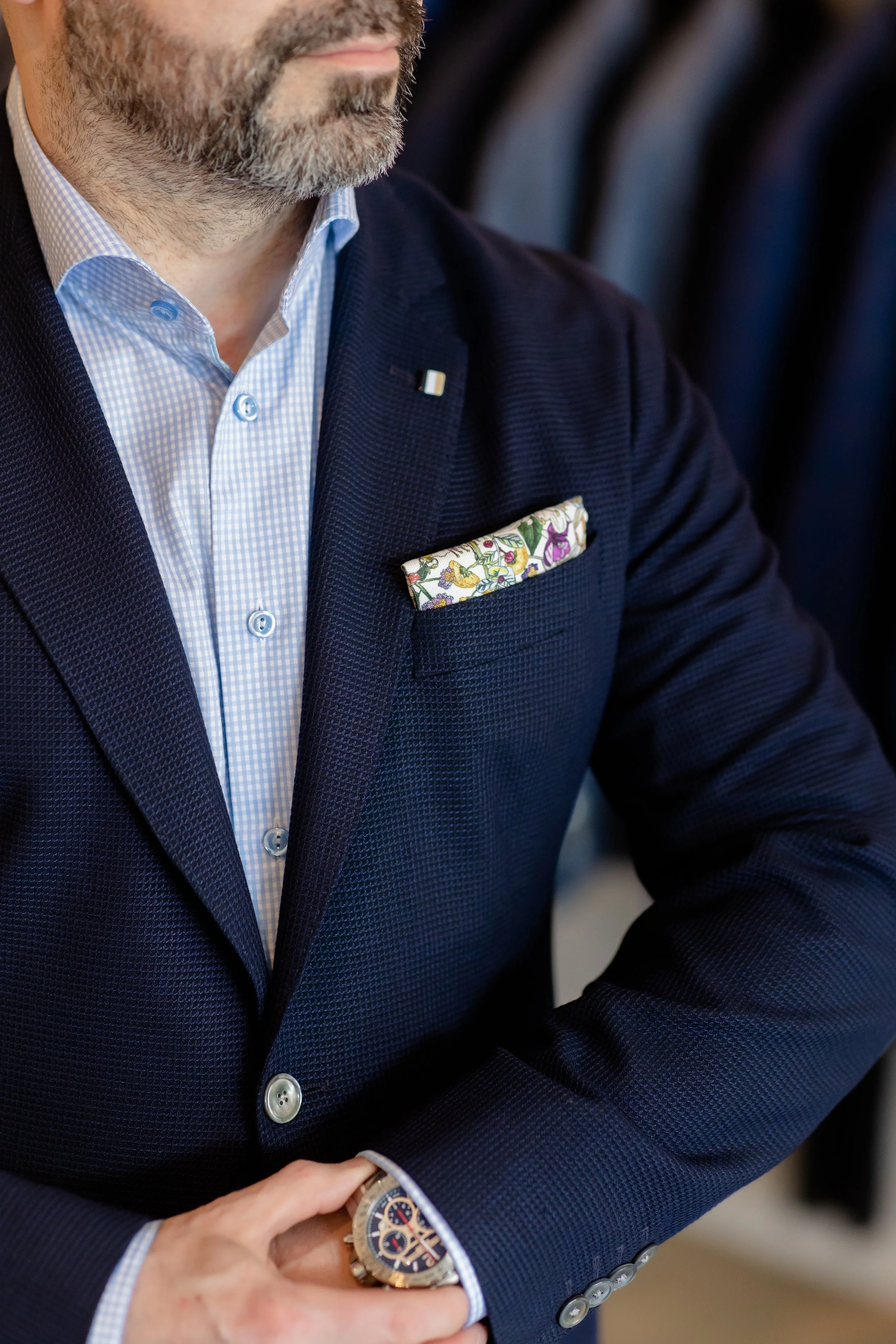a cropped image of a man wearing a blazer, dress shirt and pocket square.