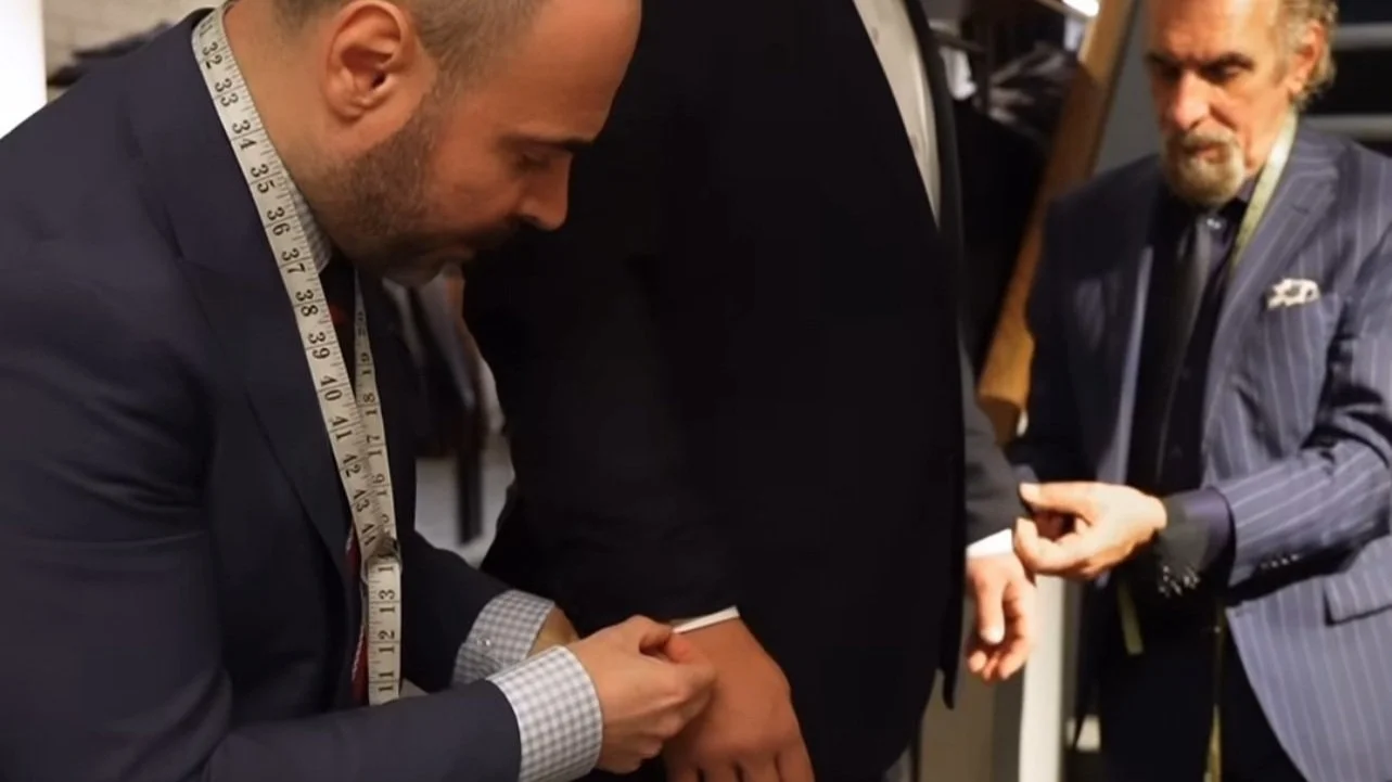 two men measuring a customer to tailor his suit