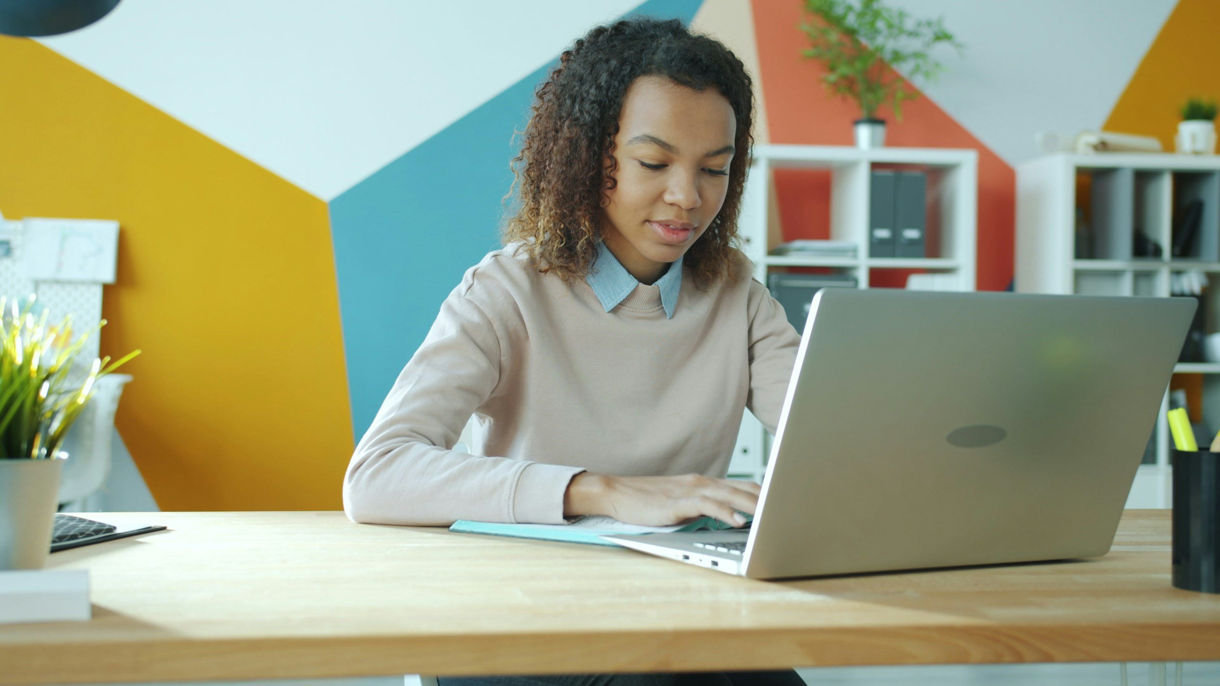 An adult watching an online lesson and taking notes.