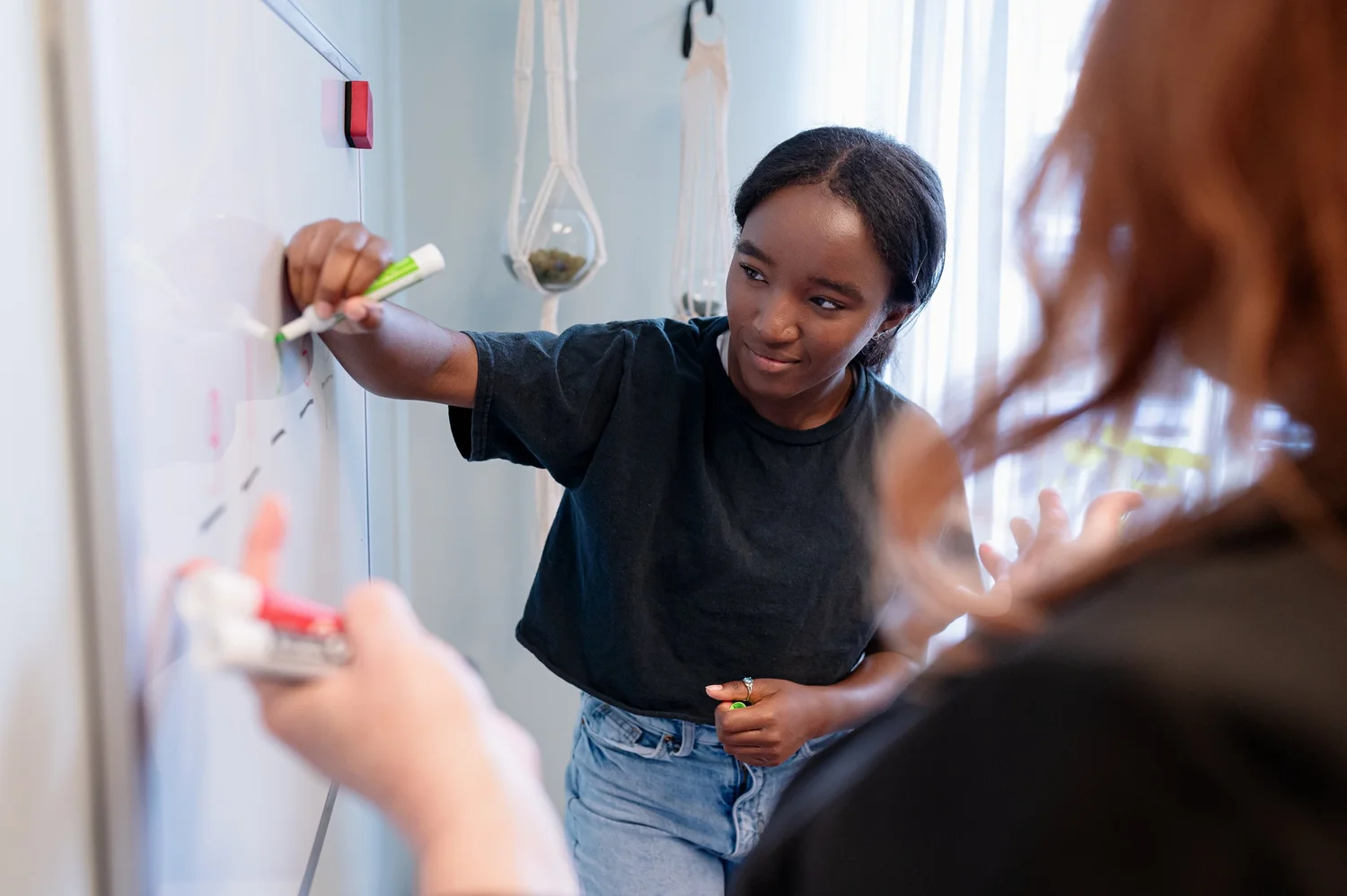 A student and professional working together at a whiteboard.