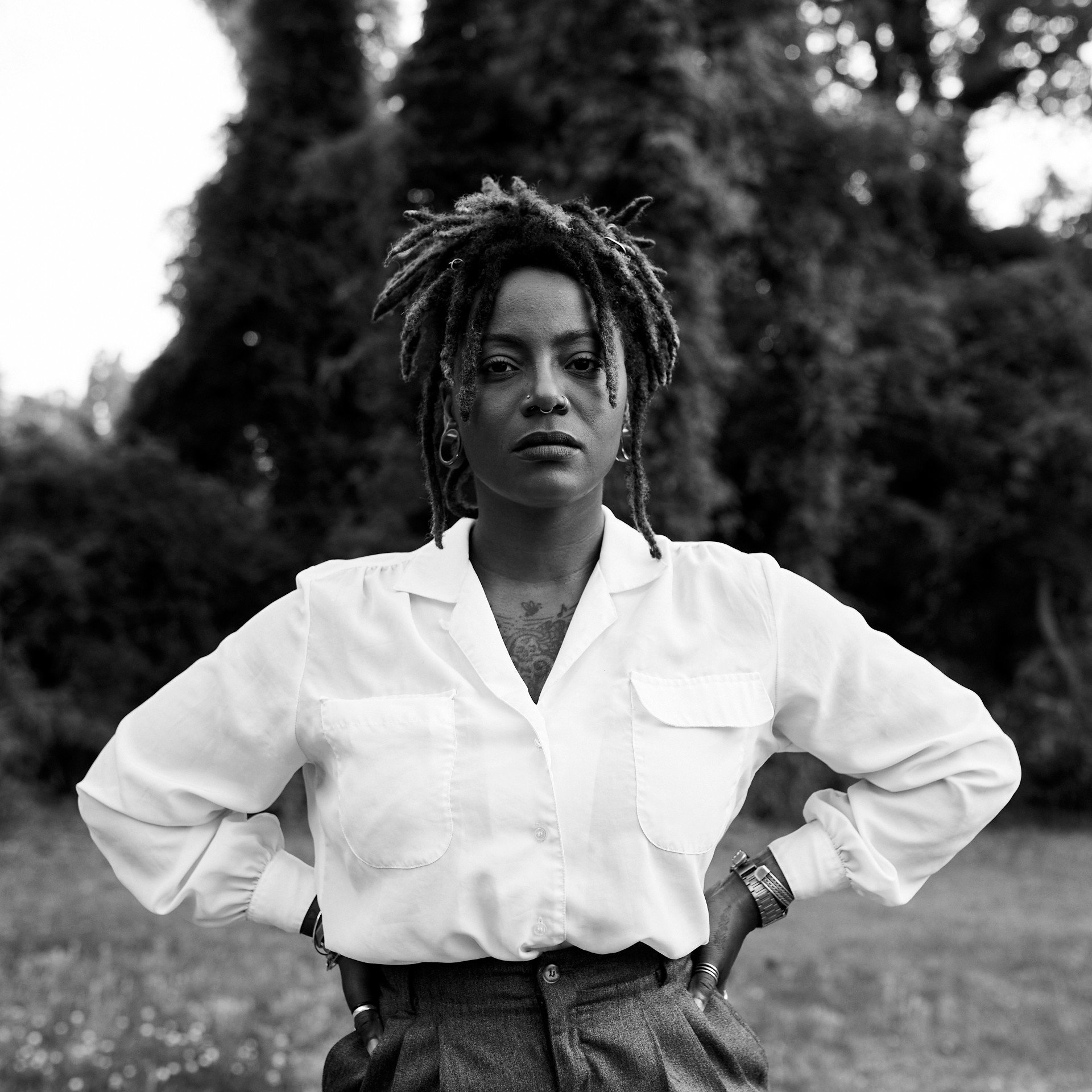 African American woman standing with her hands on her hips looking pensive.