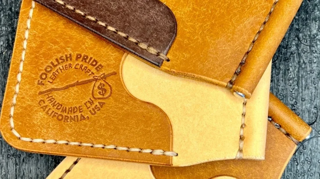 Close-up of handcrafted leather wallets with "Foolish Pride Leather Craft Handmade in California, USA" logo.