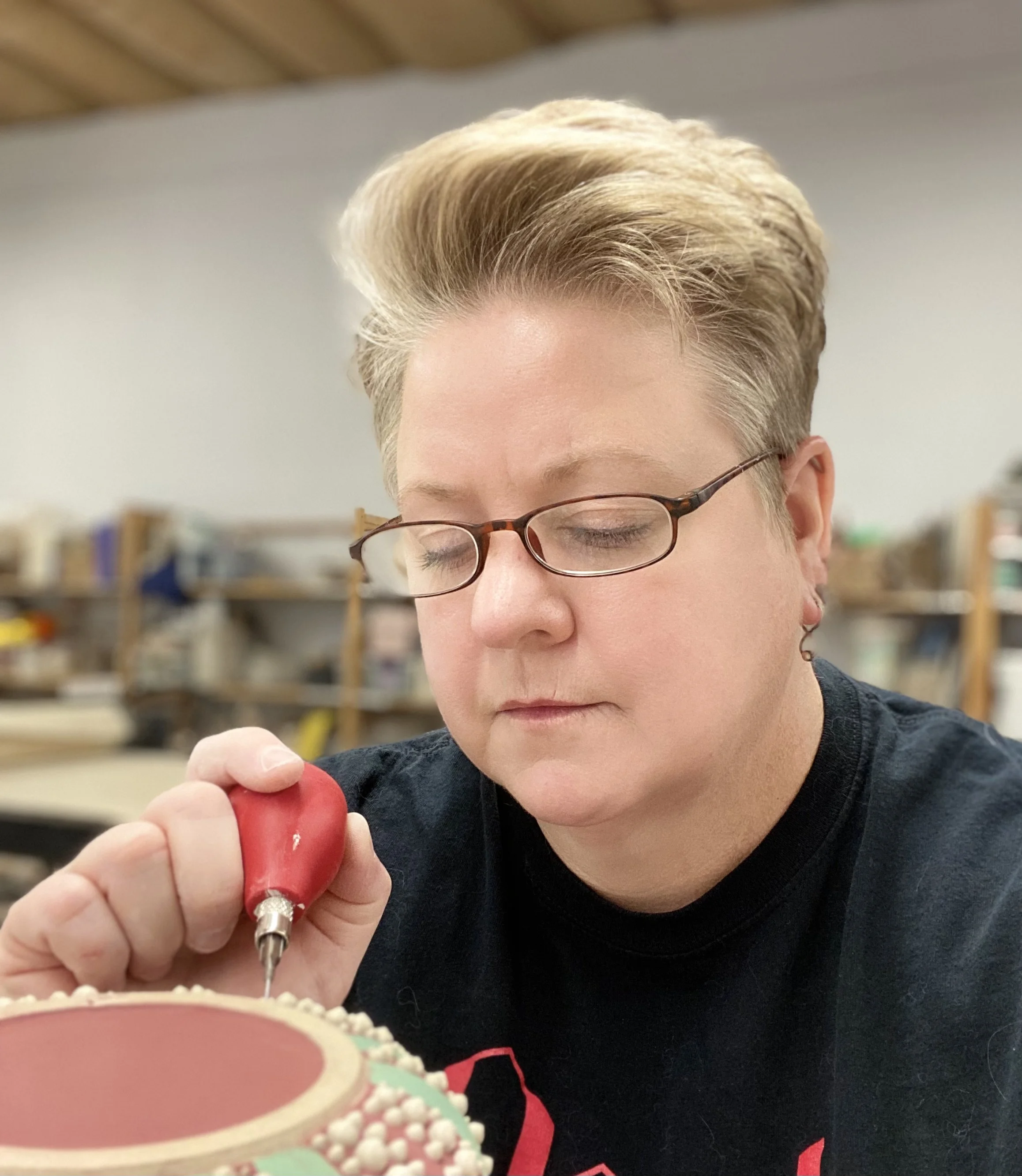 Person focusing while working with a carving tool on a decorative object.