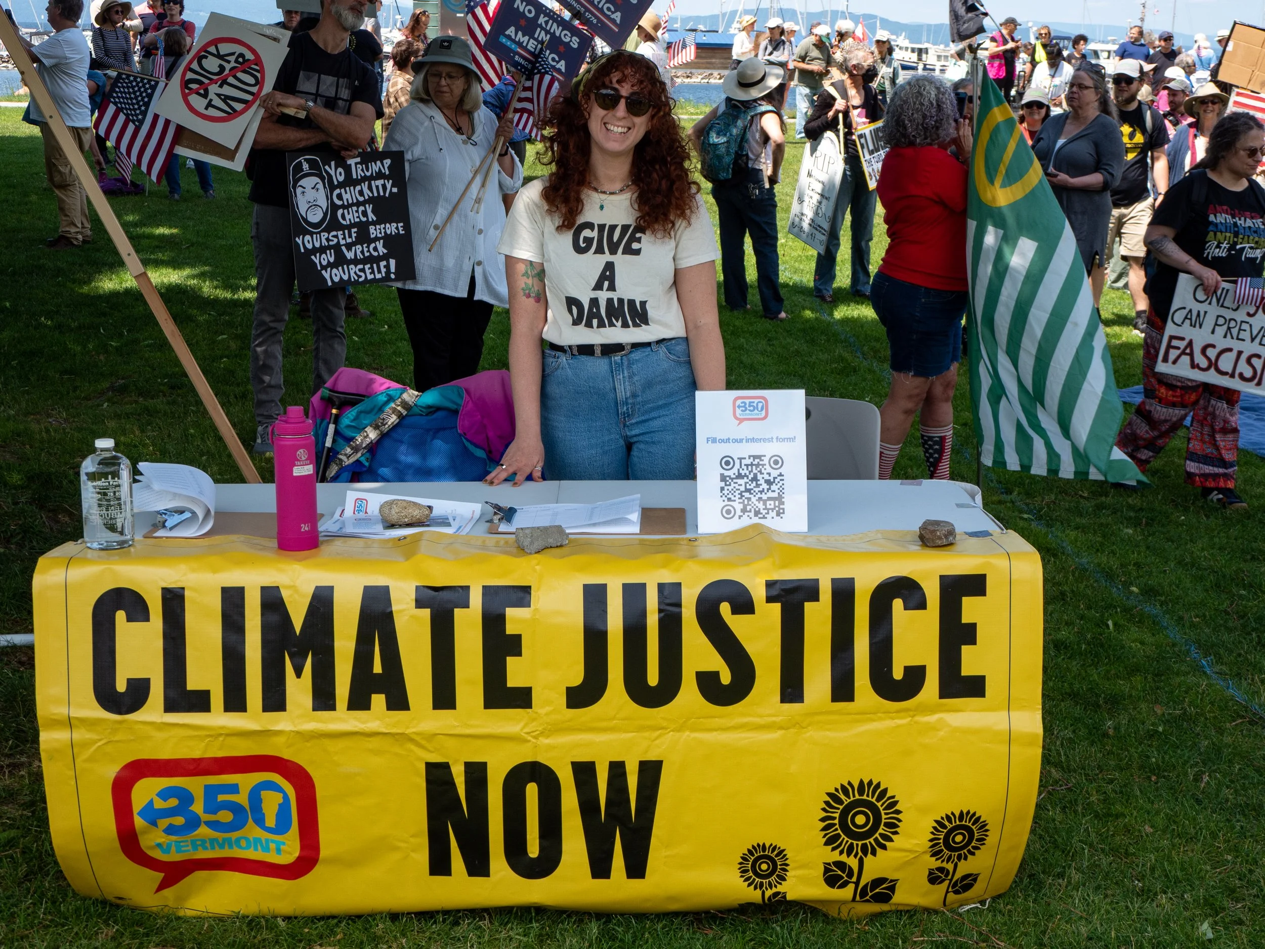 Staff member smiling at table with 'Climate Justice Now' banner