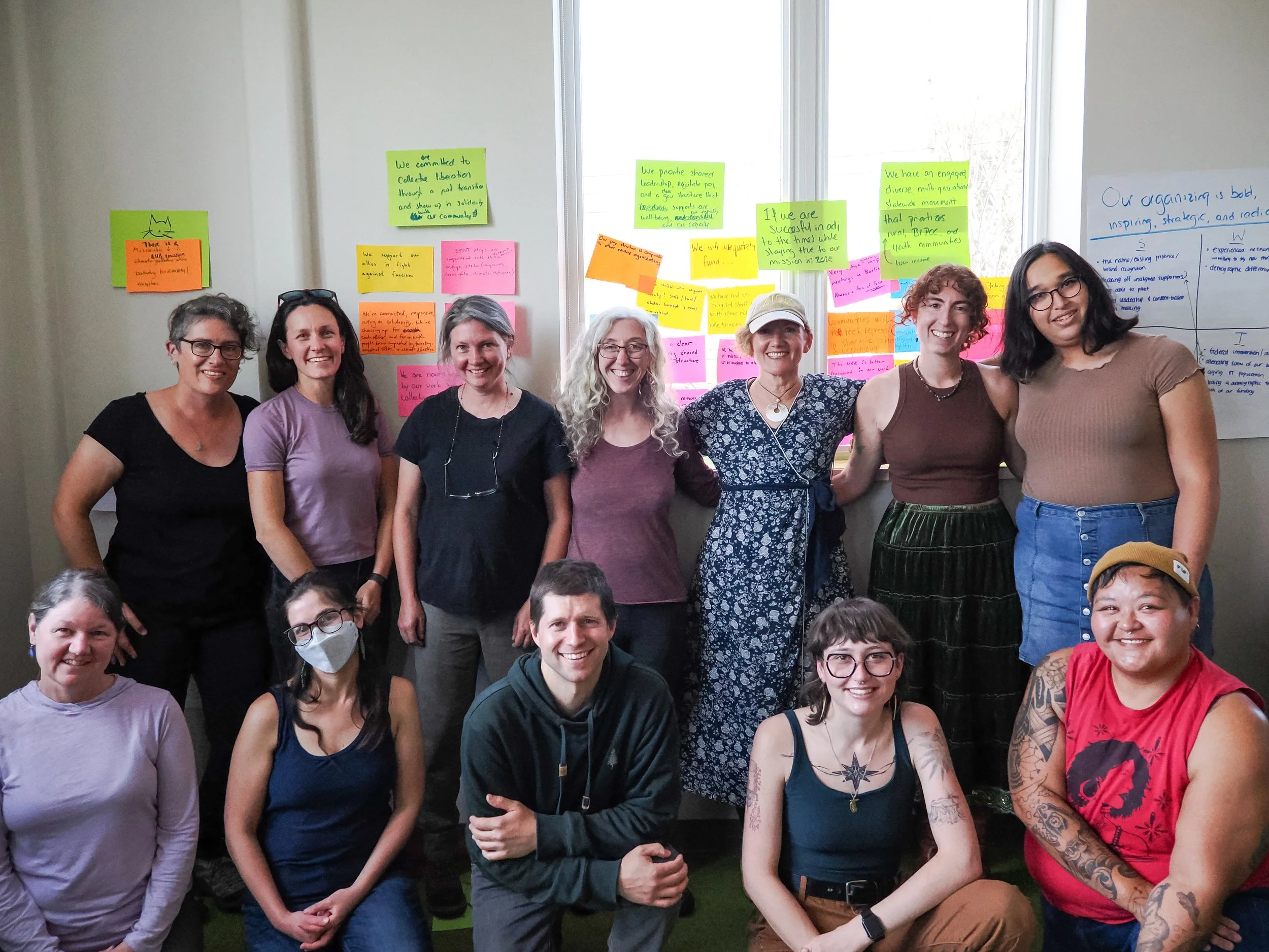 350VT's board and staff smiling for a group photo in front of a wall with post-it cards